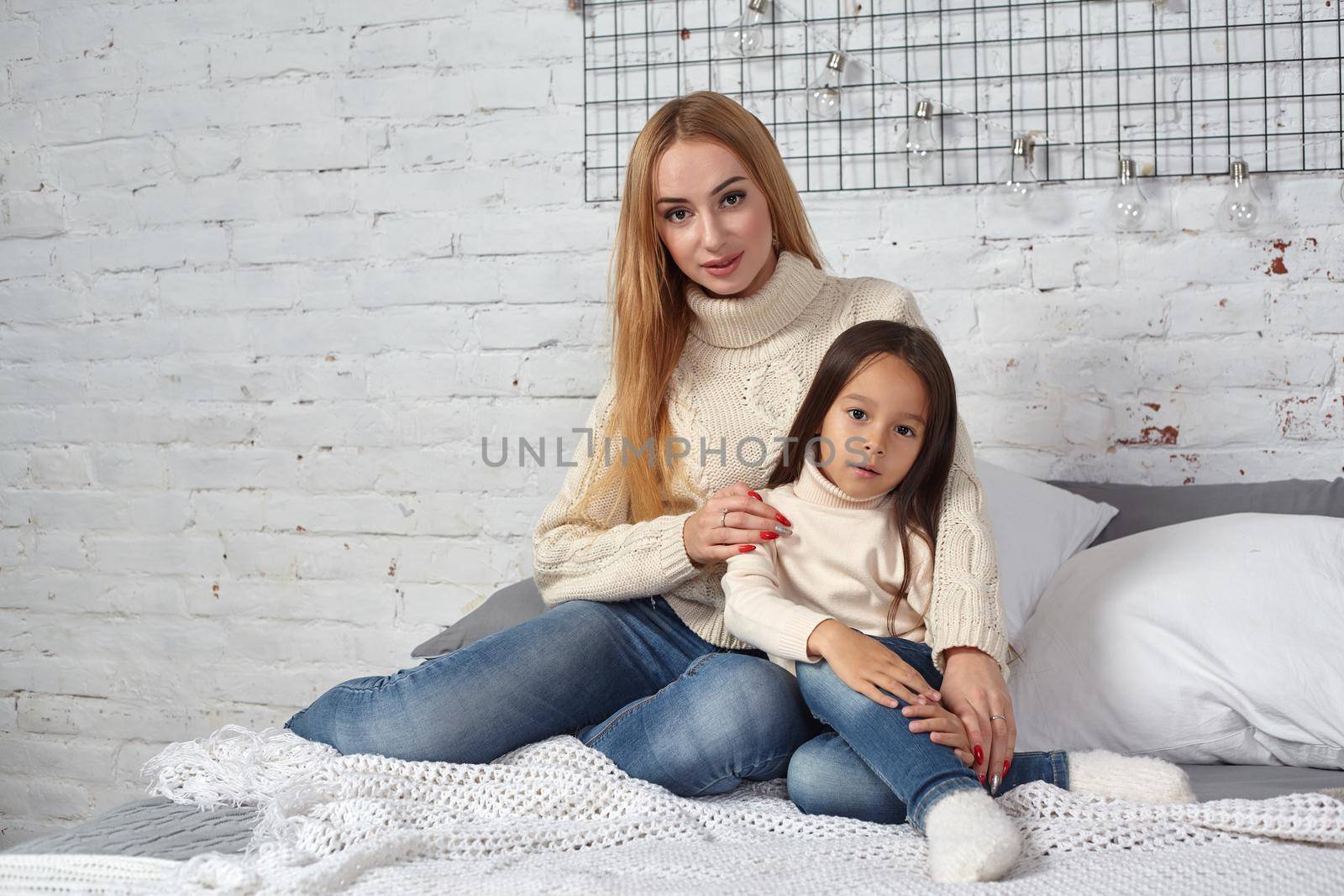 Happy loving family. Mother and her daughter child girl playing and hugging on bed