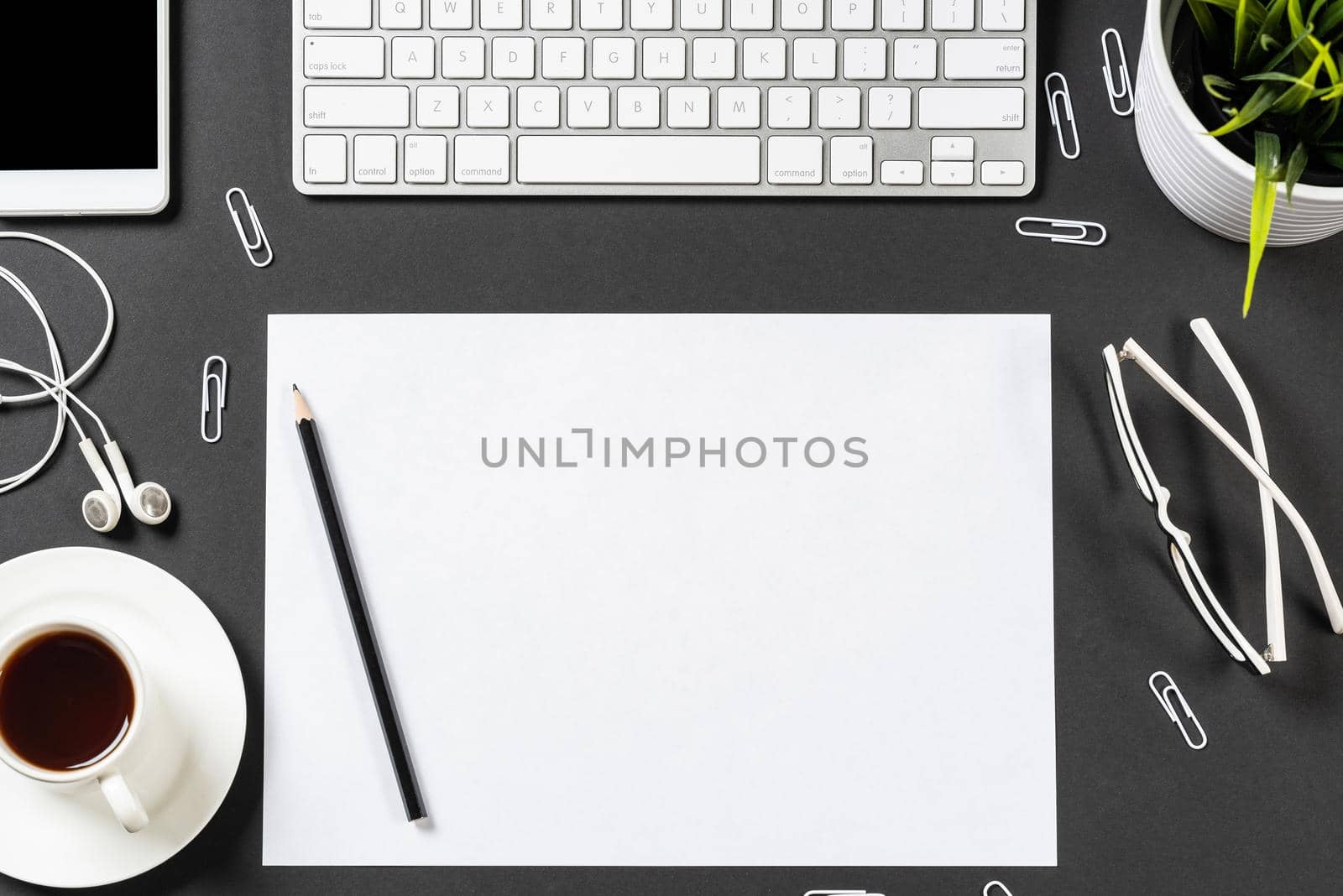 Top view of modern workplace with blank paper sheet. Flat lay black surface with smartphone, notepad and cup of coffee. Top view office workspace and freelance. Digital technology and mobile lifestyle