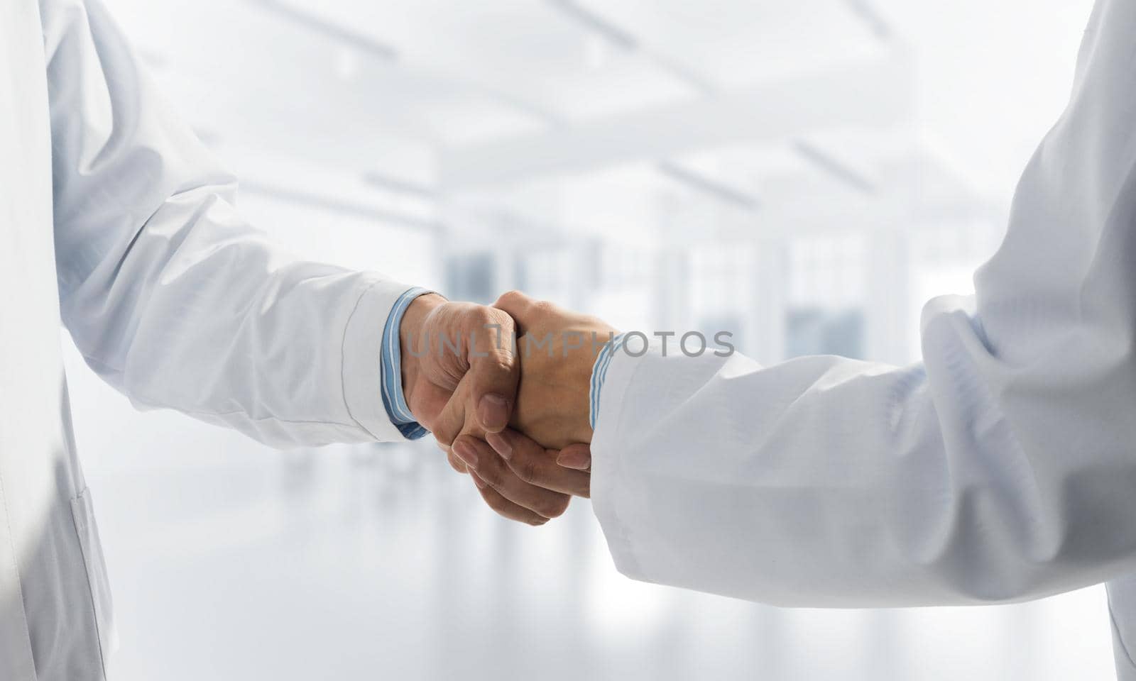 Close-up of the handshake between the two medics. Against the backdrop of the office