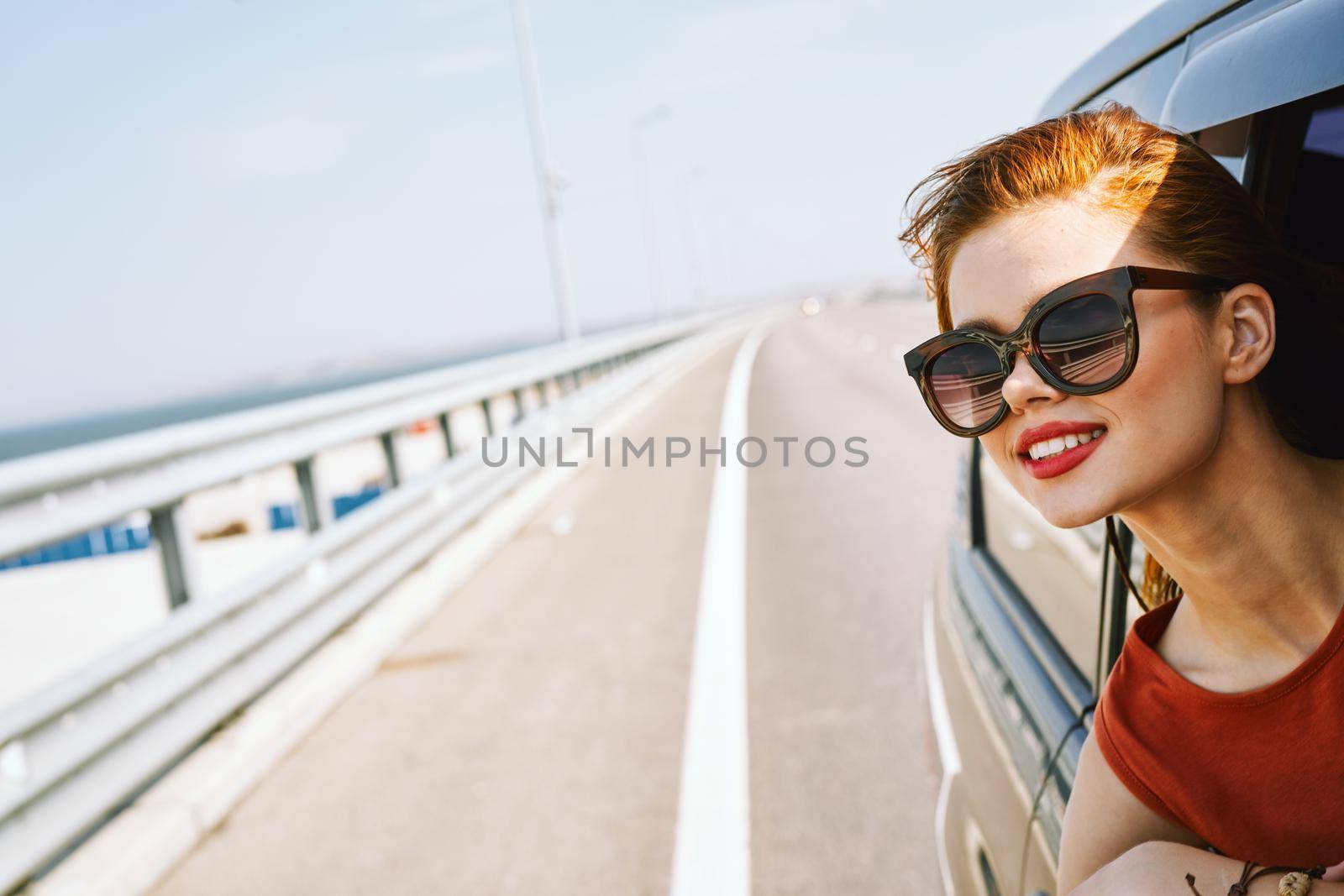 cheerful woman peeking out of the car window trip adventure lifestyle. High quality photo