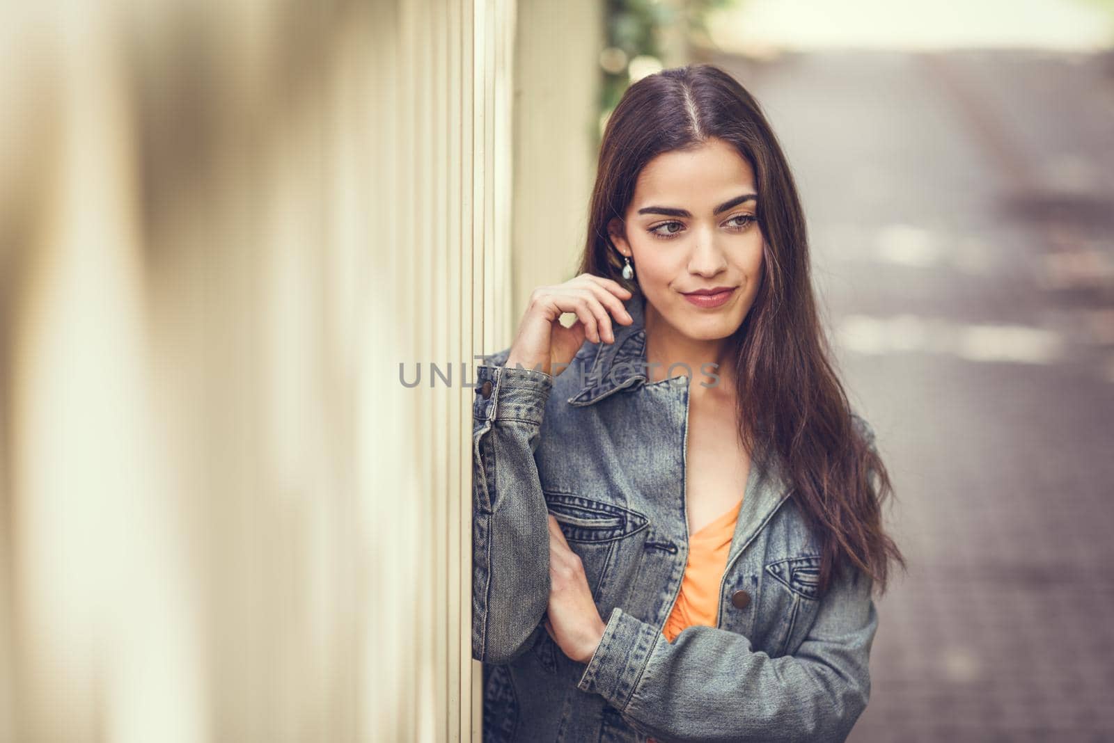 Young woman with nice hair wearing casual clothes in urban background. Happy girl with wavy hairstyle.
