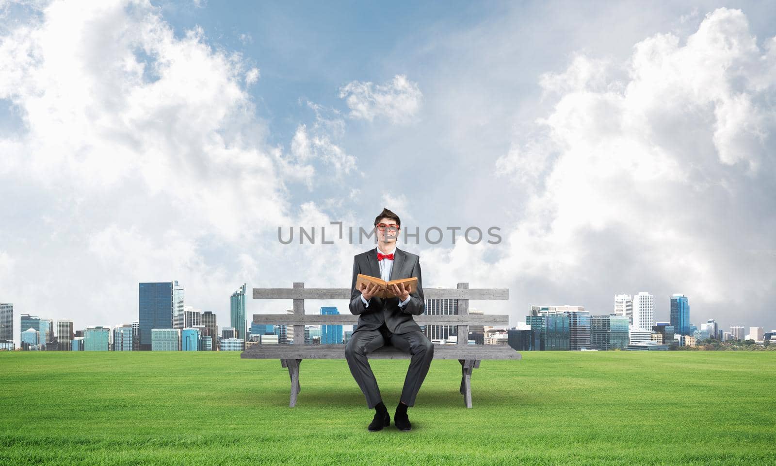 Young student sits on a wooden bench with a book