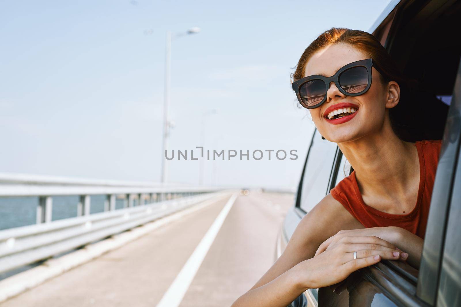 a woman is driving in a car on the road and looking out of the window. High quality photo