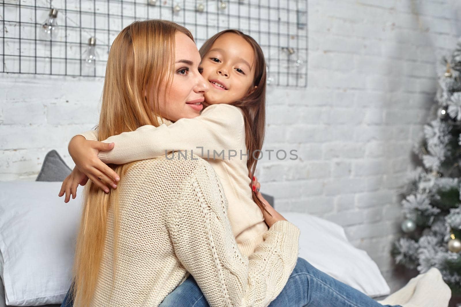 Beautiful young woman and her charming little daughter are hugging. by nazarovsergey