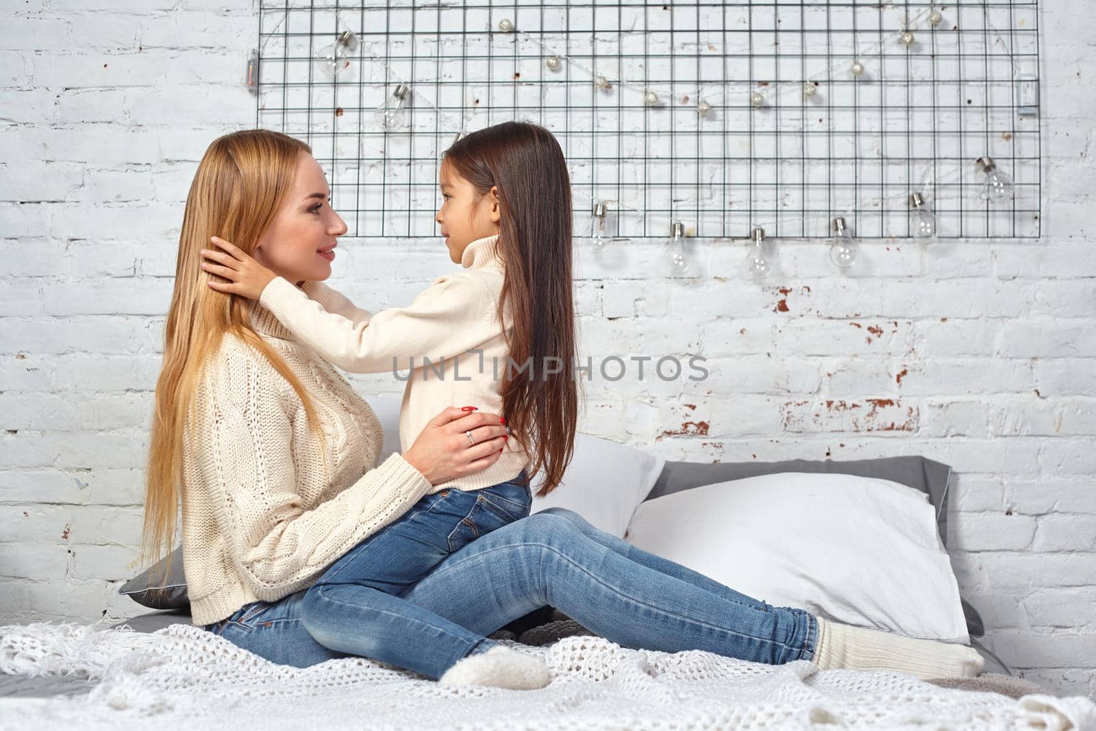 Happy loving family. Mother and her daughter child girl playing and hugging on bed