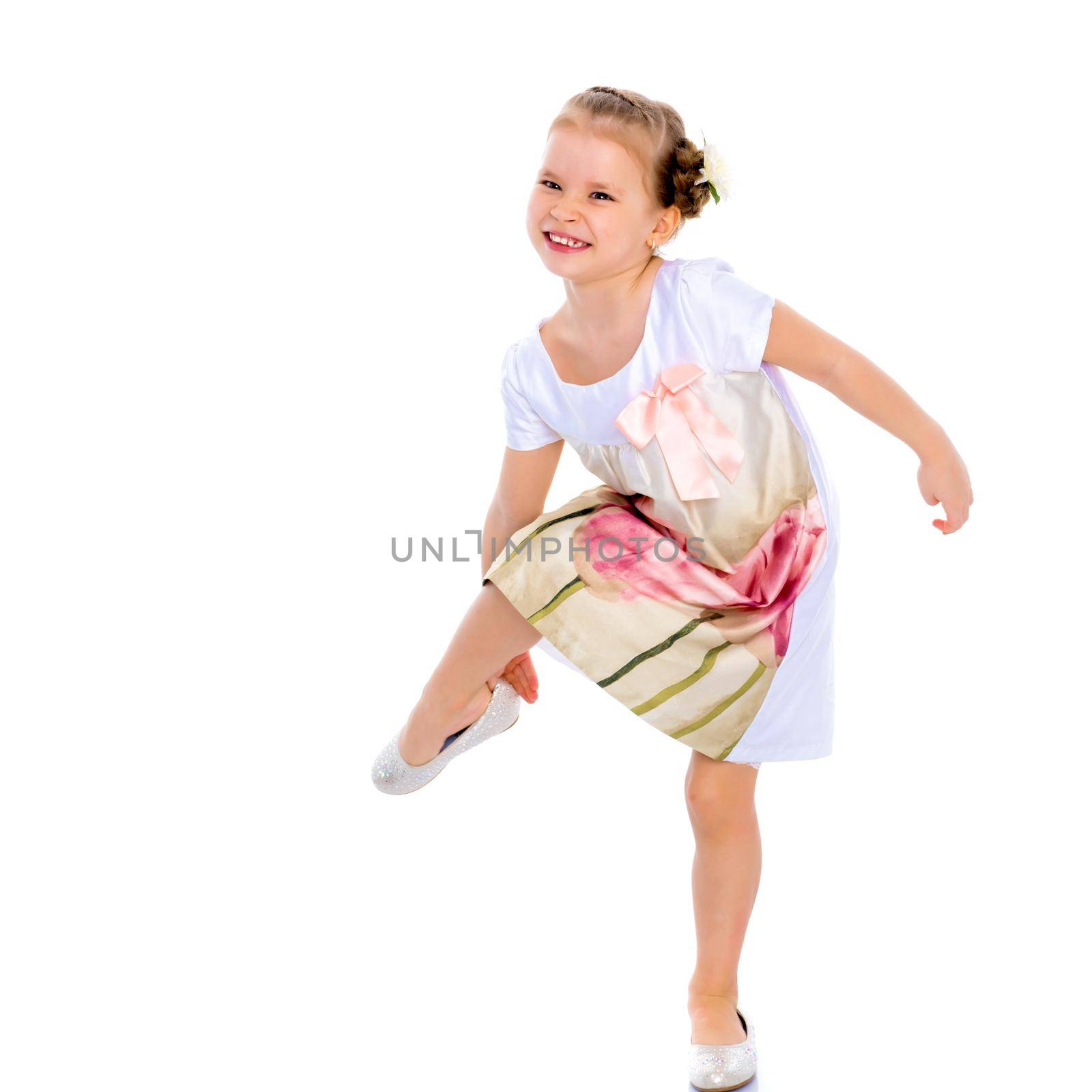 The little girl puts on her shoes. The concept of beauty and fashion, happy childhood. Isolated on white background.