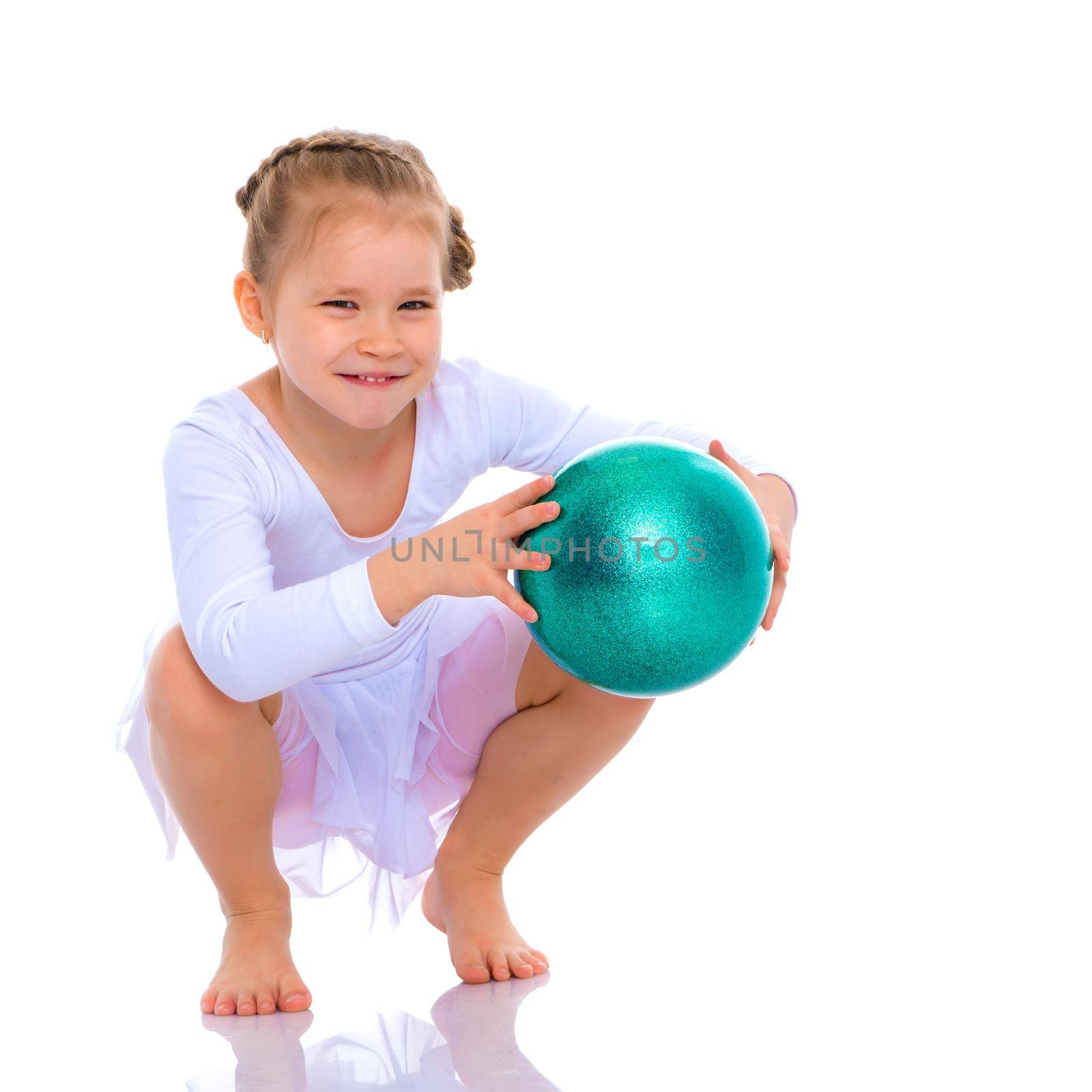 A charming little girl is engaged in fitness with a ball. The concept of gymnastics, health and sports. Isolated on white background.