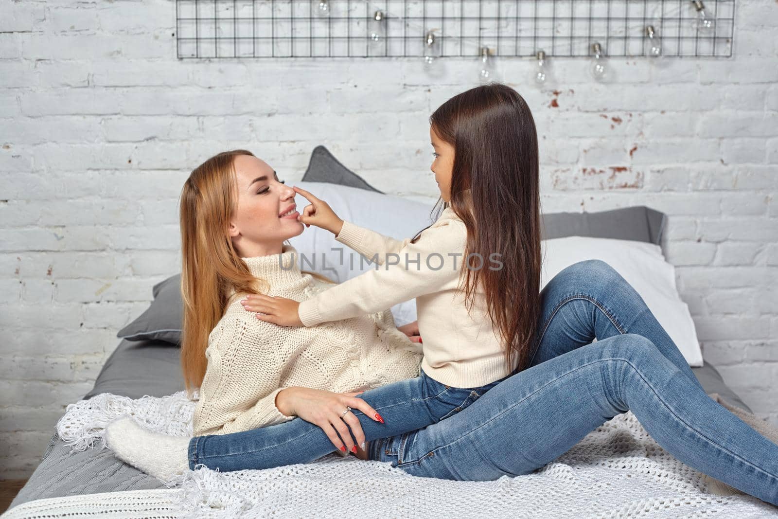 Happy loving family. Mother and her daughter child girl playing and hugging on bed