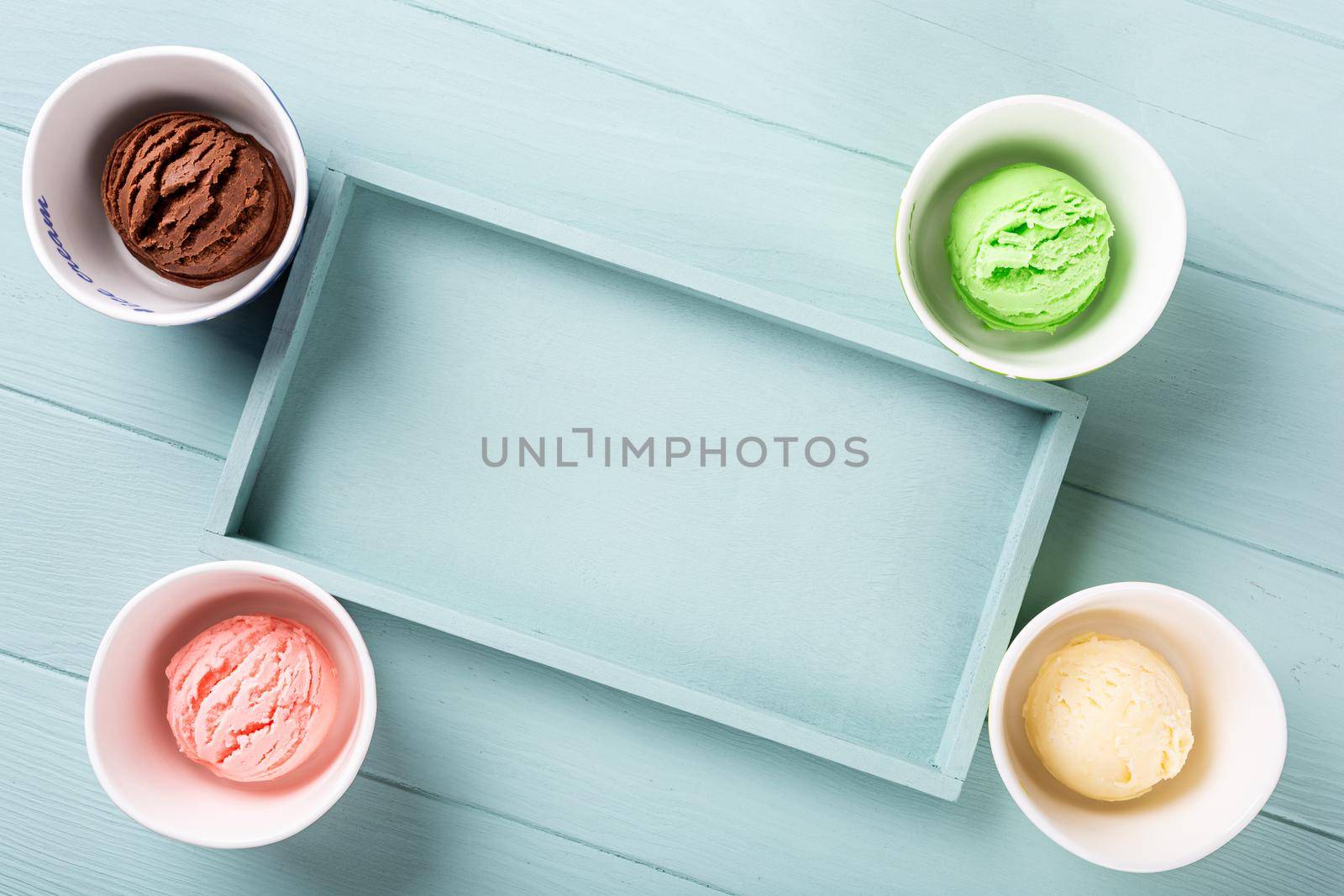 Flat lay, overhead shoot of homemade assorted ice cream on light blue wooden background. Healthy summer food concept. Top view, copy space.