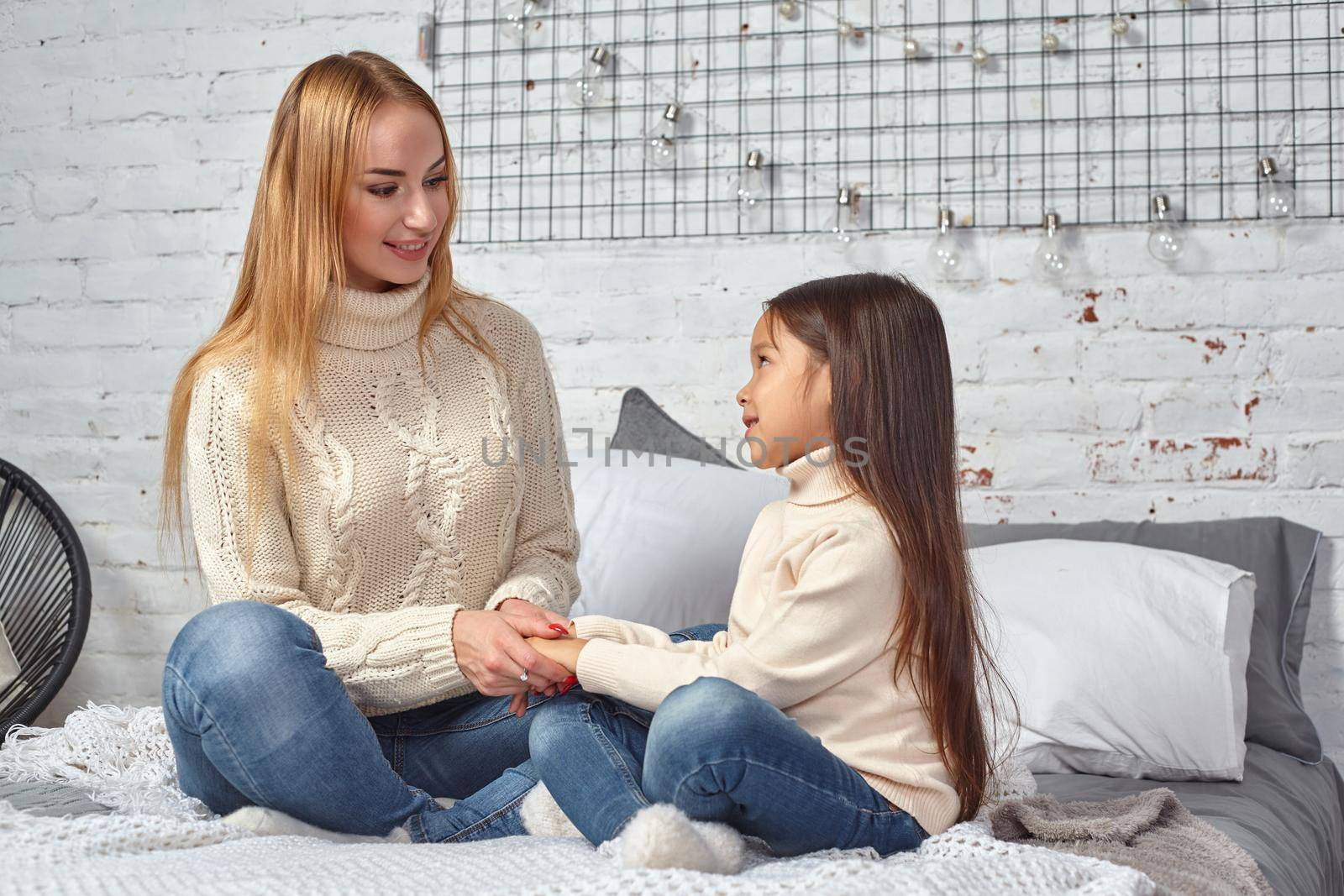 Happy loving family. Mother and her daughter child girl playing and hugging on bed