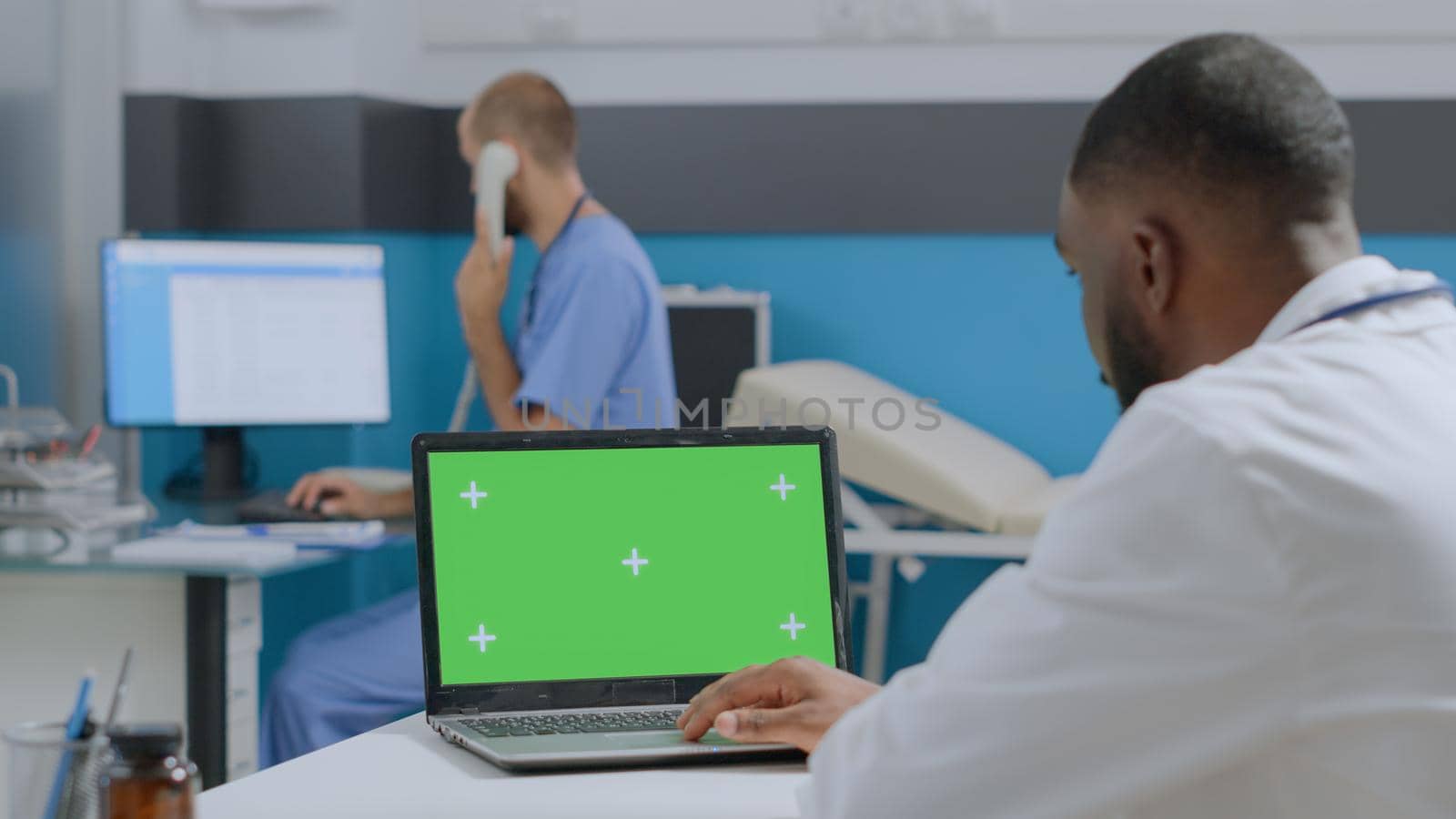 African american doctor looking at mock up green screen chroma key laptop computer by DCStudio