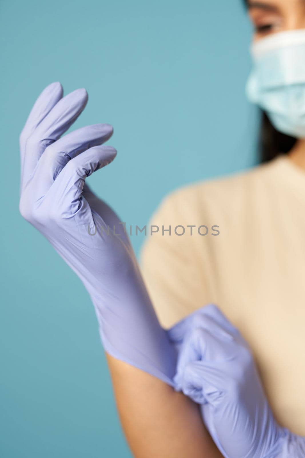 Close up of woman hands in protective gloves on a blue background in the studio. Copy space. Quarantine, epidemic concept