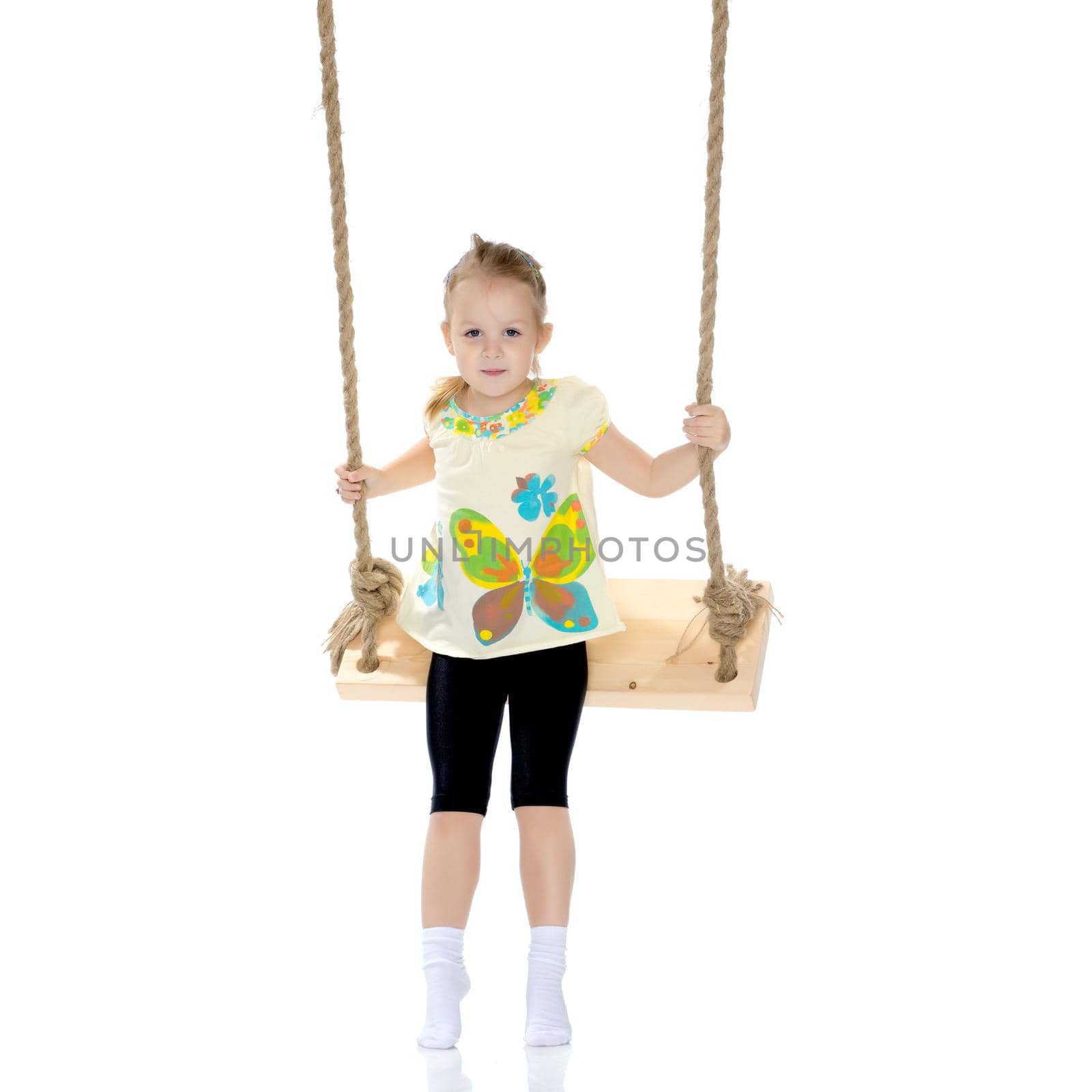 Adorable little girl swinging on a swing. She is happy to have fun and show how she can do it. The concept of summer recreation and harmonious development of the child. Isolated on white