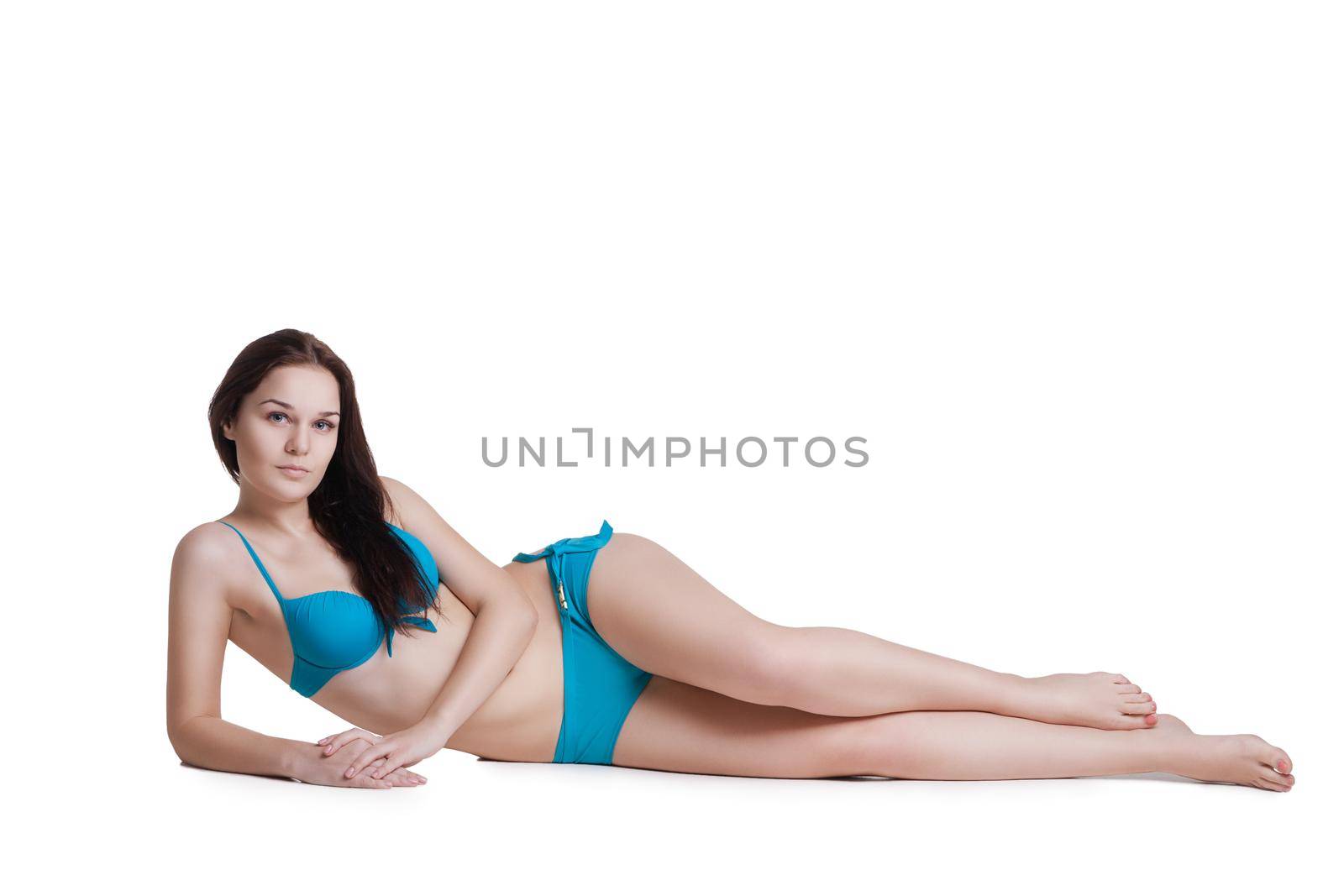 Portrait of a beautiful brunette girl wearing blue bikini posing at studio