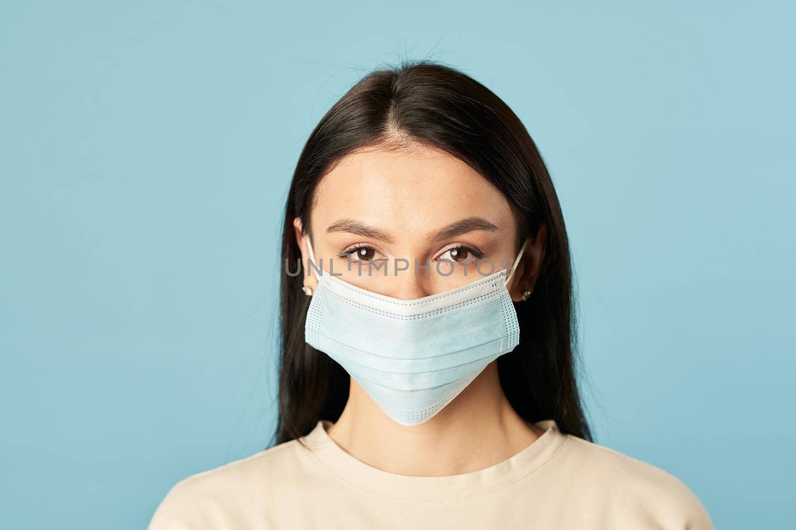 Young lady standing and looking at camera while wearing protective face mask. Quarantine, coronavirus concept. Copy space