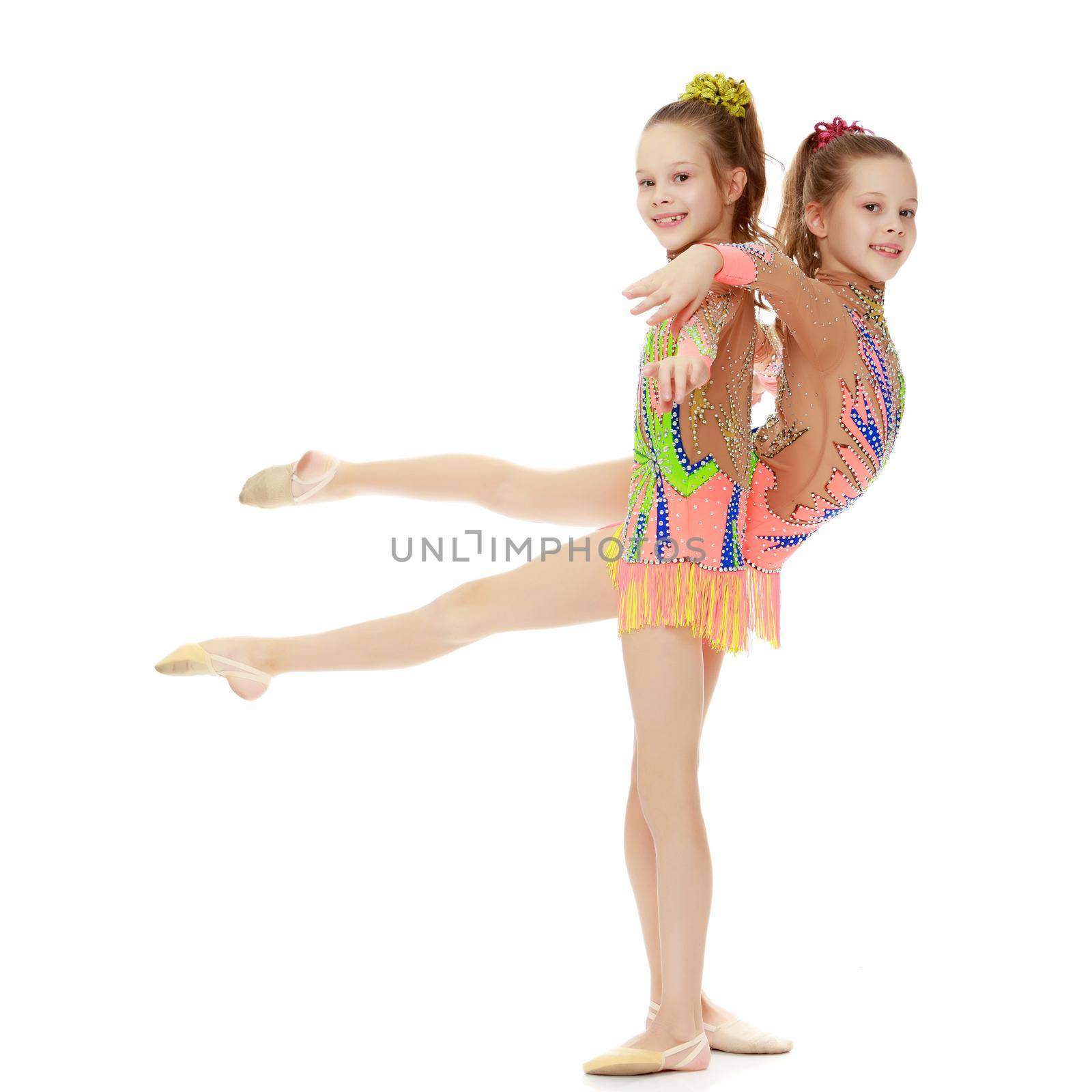 Two adorable little twin girls, gymnastics in the sports school. Girls beautiful gymnastic leotards. They do the splits.Isolated on white background.