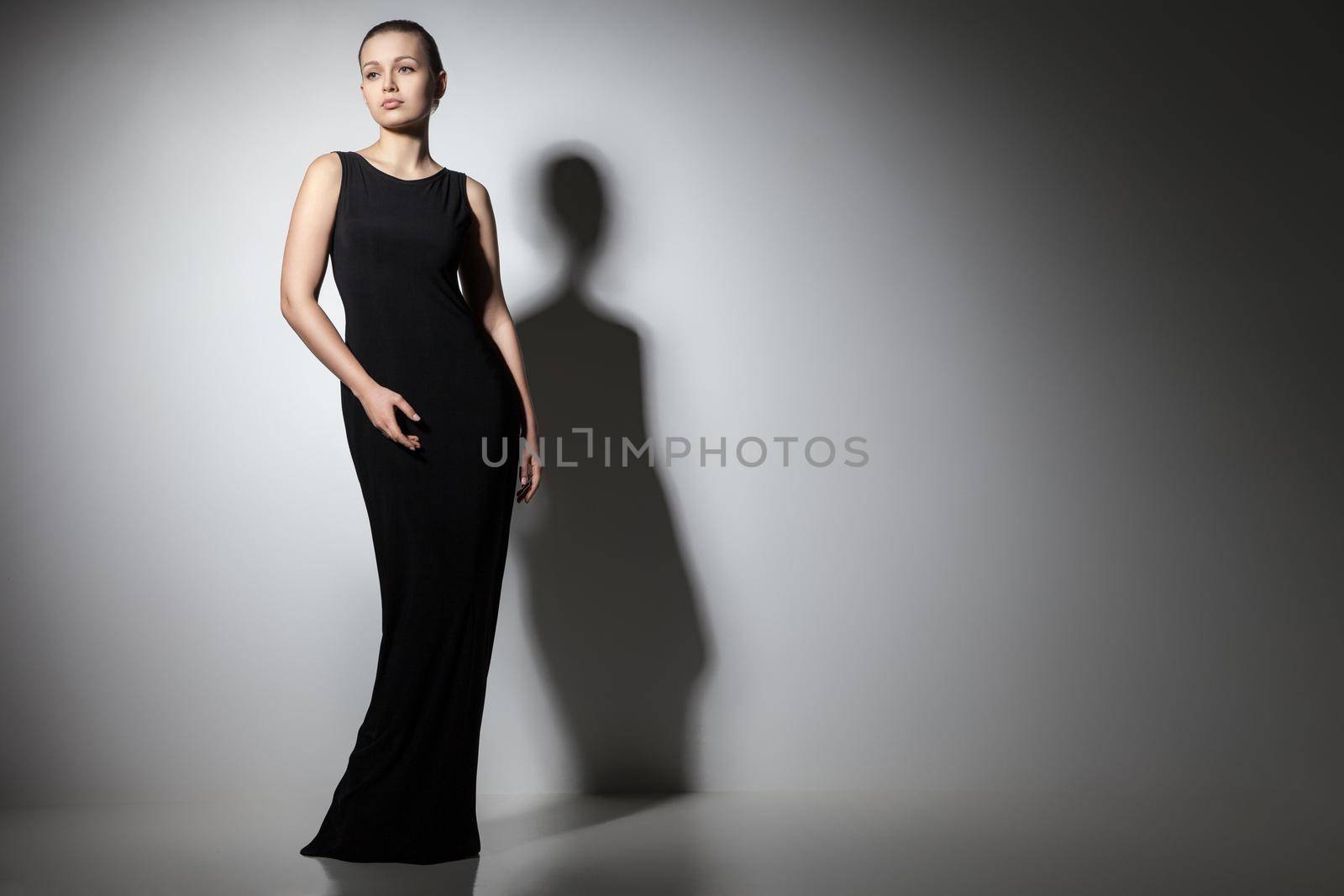 beautiful woman model posing in elegant black dress in the studio