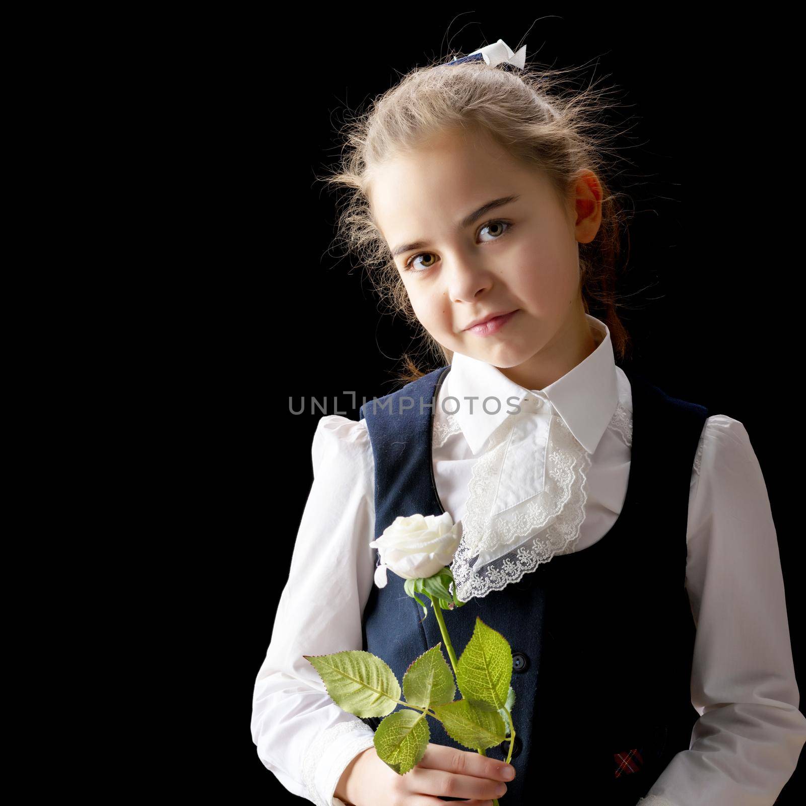 Beautiful little girl with a flower in her hand. The concept of style and fashion. On a black background.