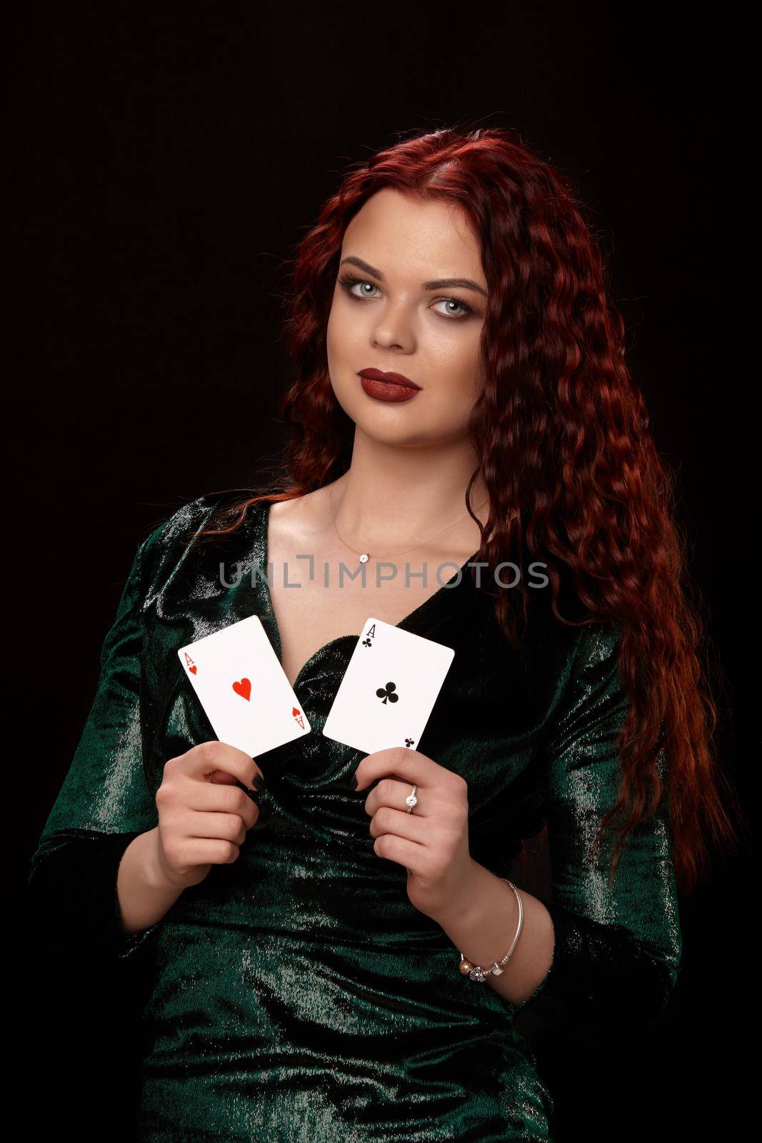 Beautiful redheaded woman in a black dress with a playing cards, over black. Win casino holdem poker slots
