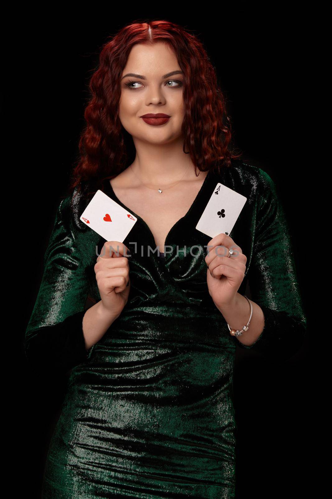 Charming redheaded woman whith a curly hair posing with a playing cards in her hands and smiling, on black background Win casino holdem poker slots