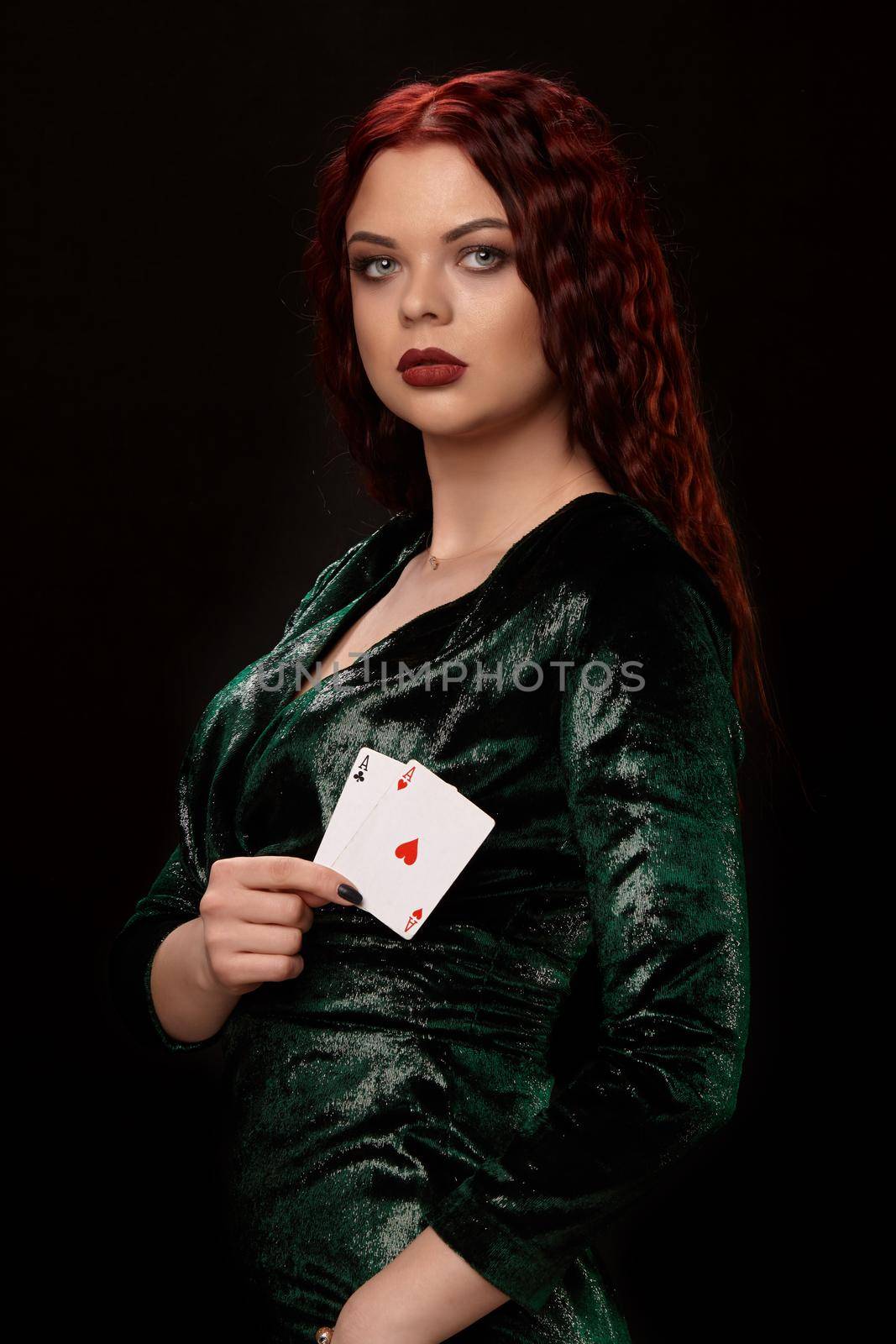 Beautiful redheaded woman with a playing cards in her arms turned sideways over black. Win casino poker slots