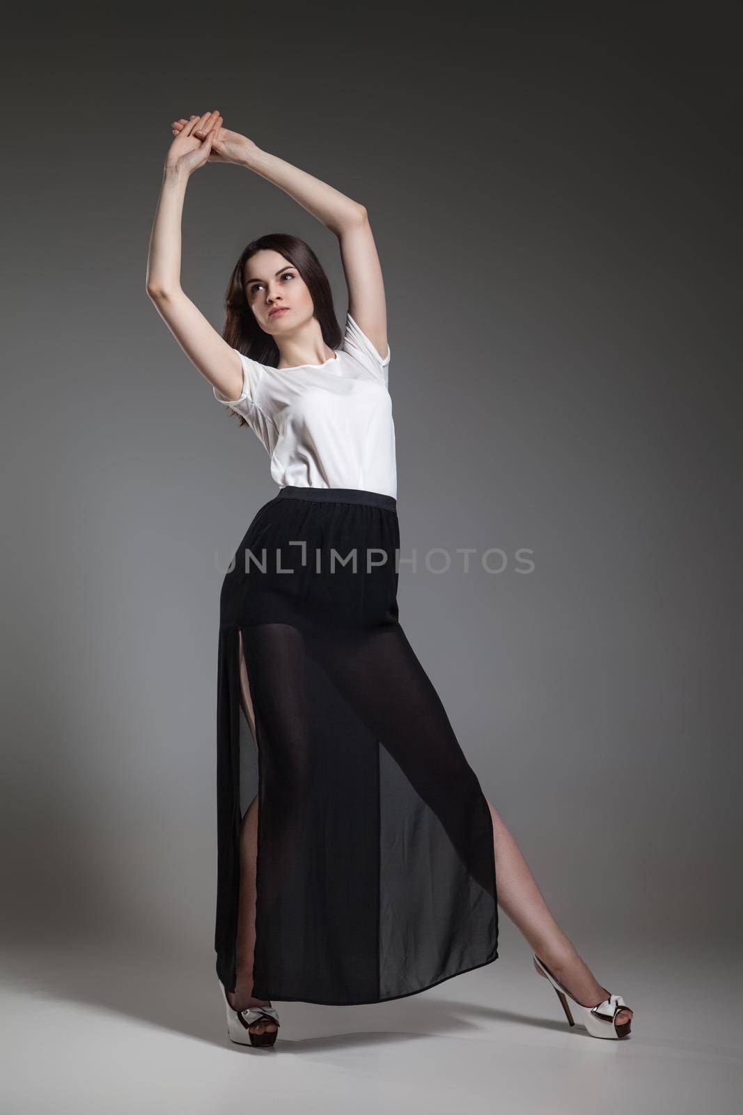 Beautiful model in white top and black skirt posing on grey background by Julenochek