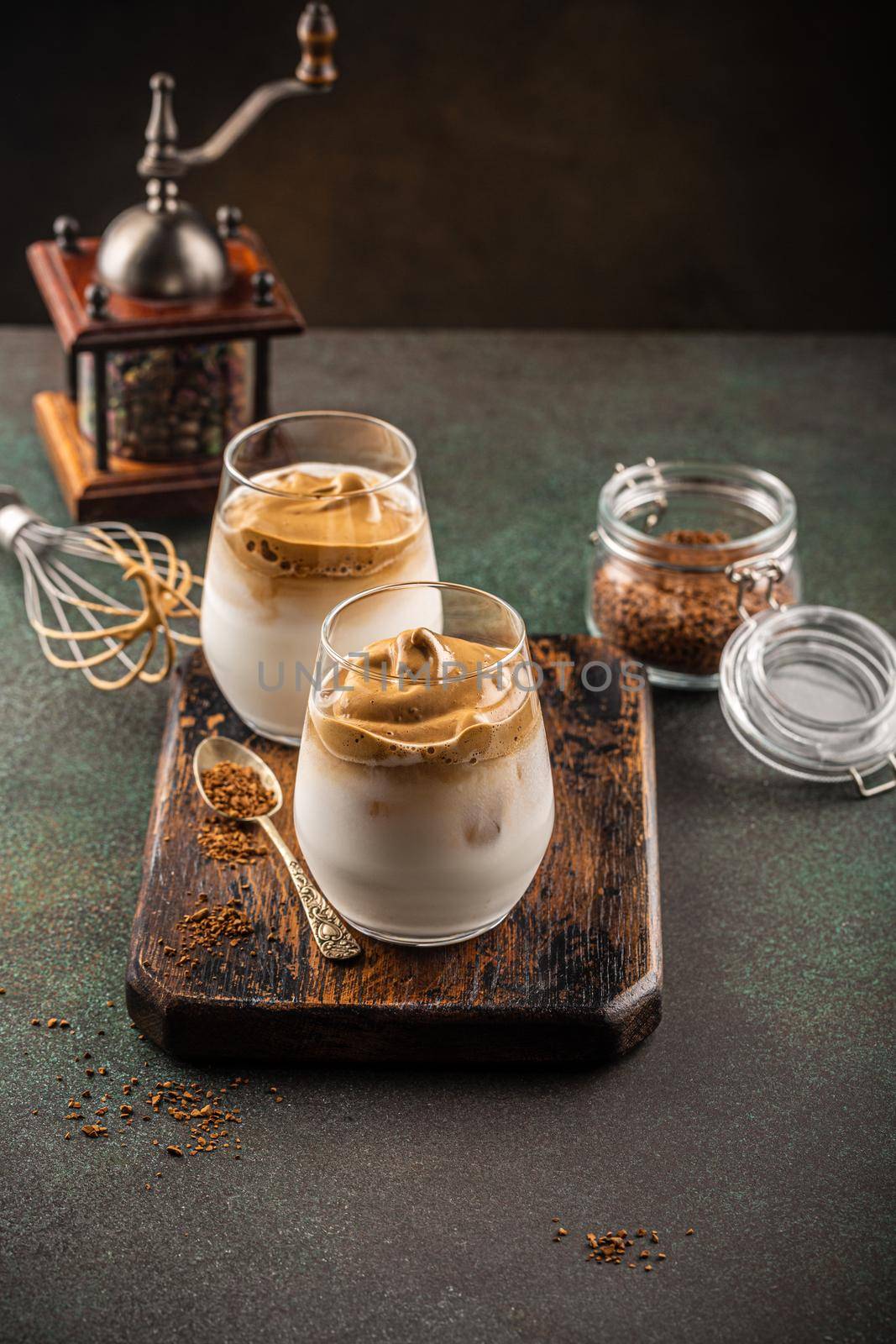 Korean trendy drink dalgona coffee from instant coffee, milk and ice on old wooden board. Modern drinks concept with copy space.