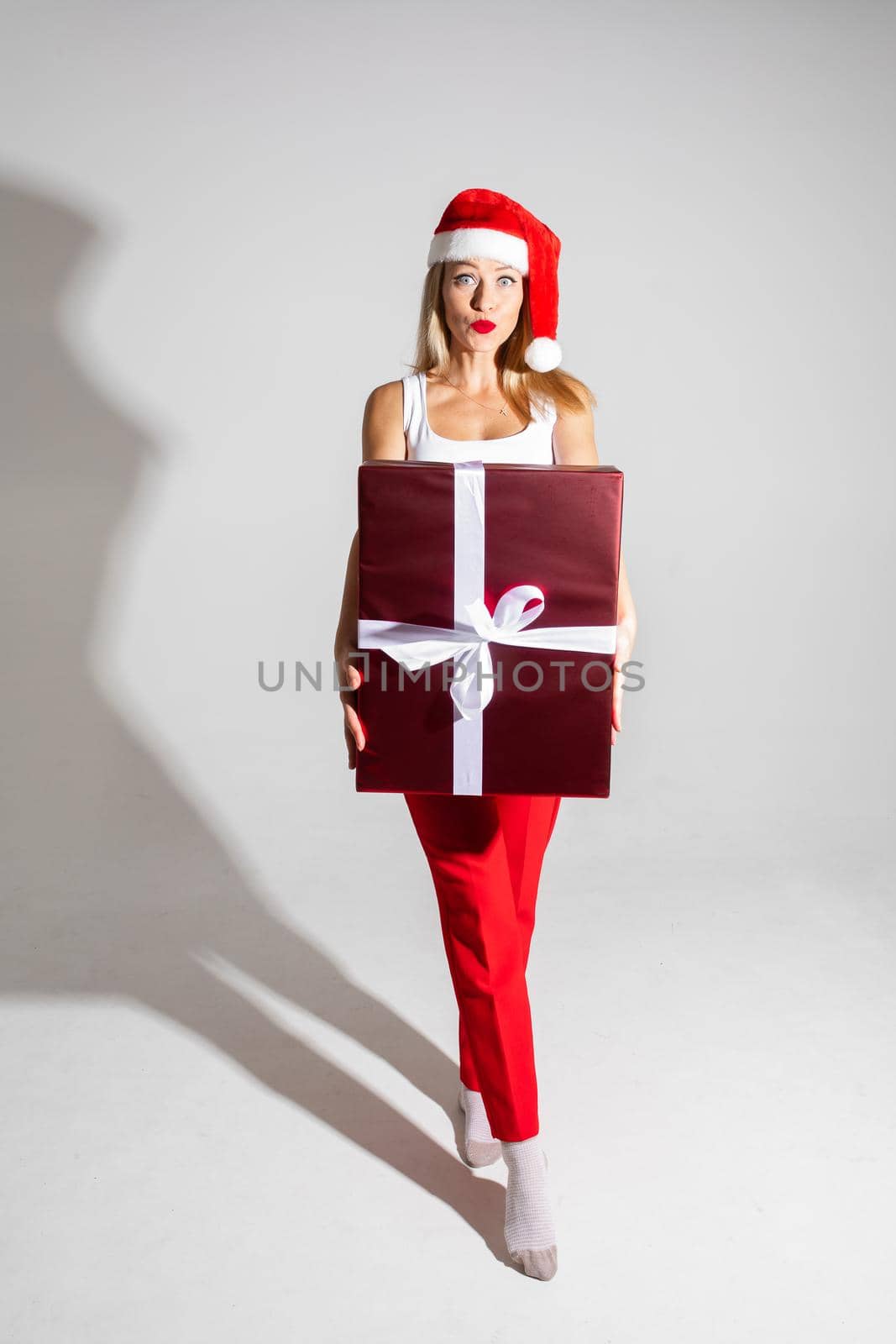 handsome woman with red and white christmas hat holds a big gift