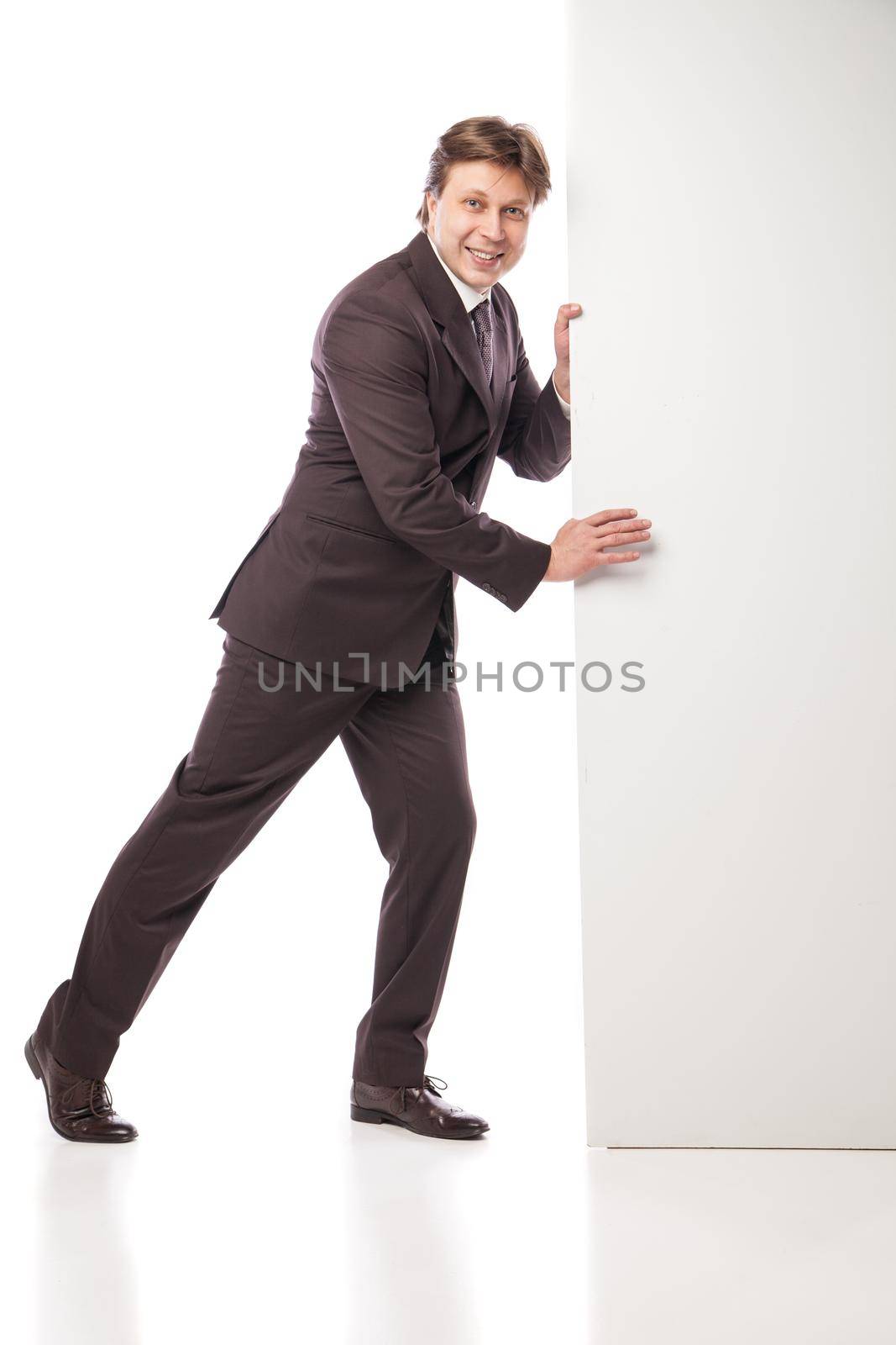 Business man holding empty board and pointing to it while smiling to camera on white background