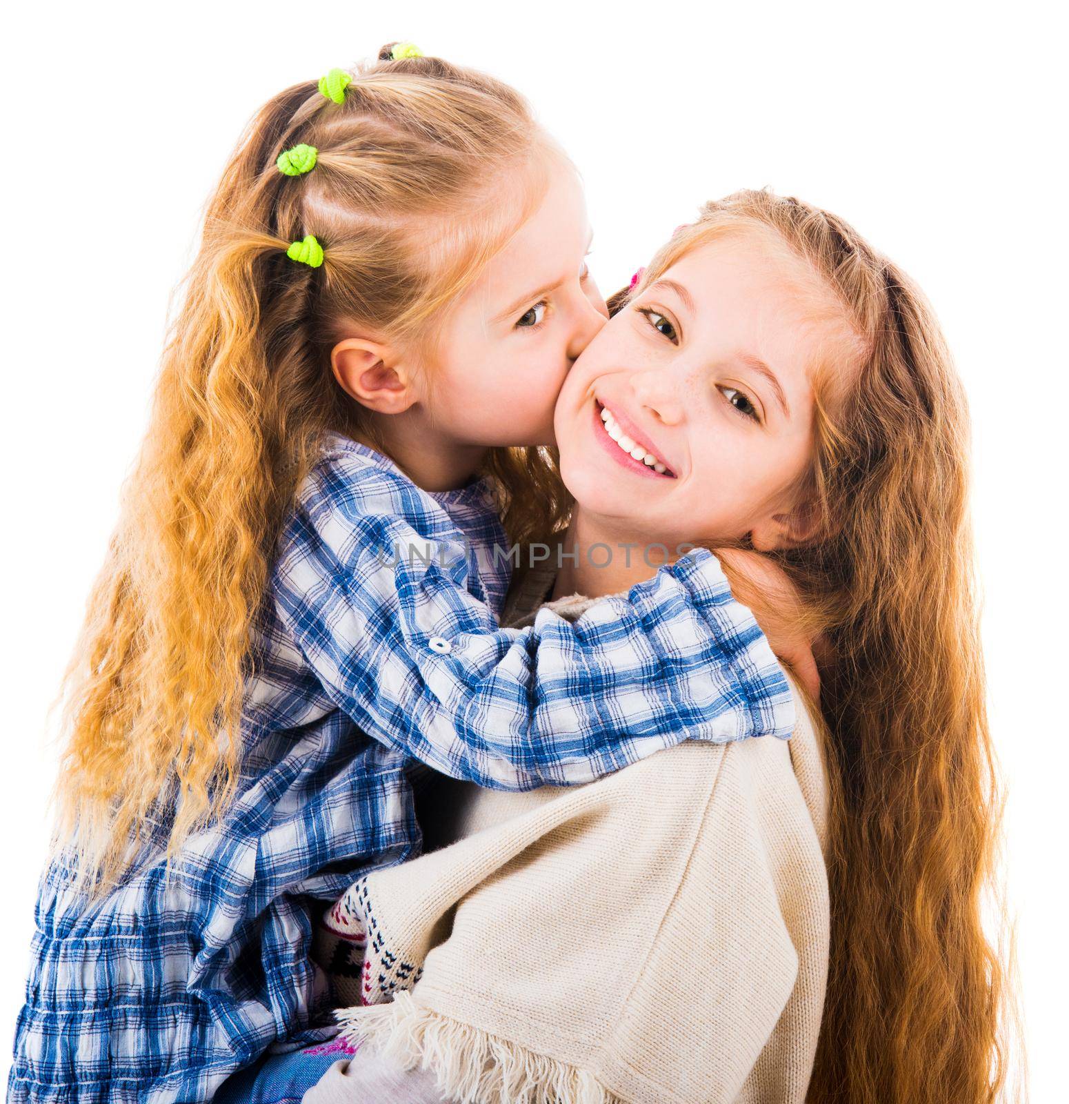Cute little girl hugging and kissing her older sister, isolated on a white background