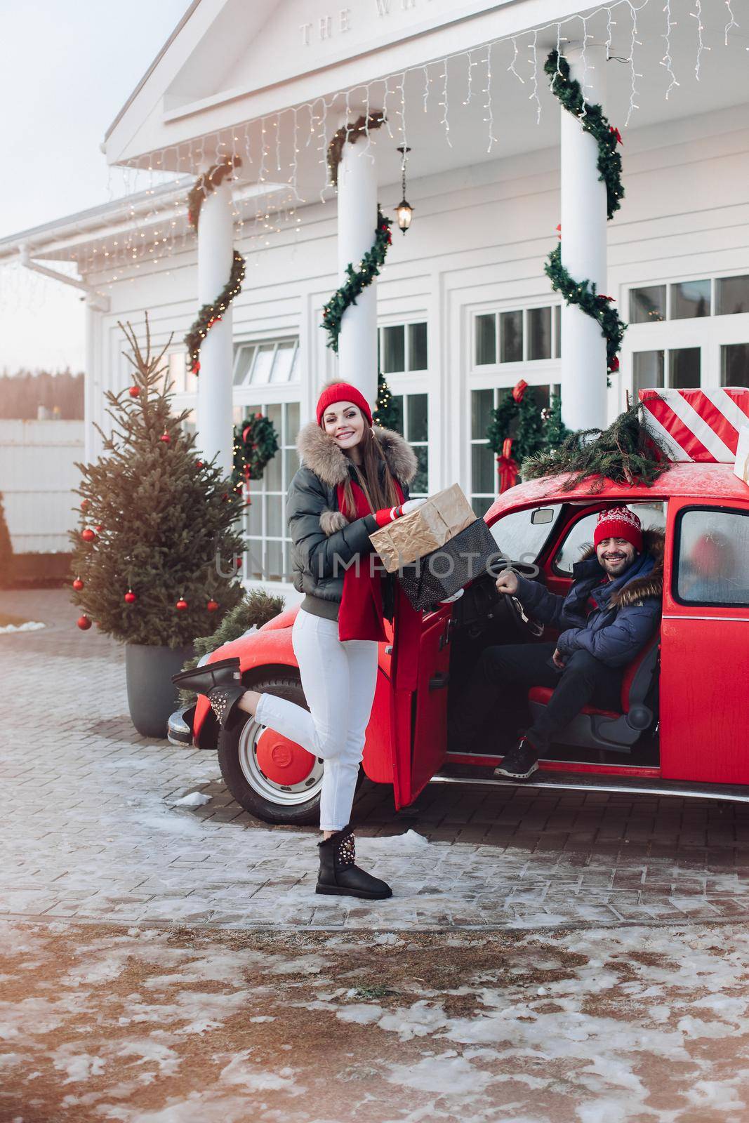 Young couple buys Christmas presents for their family and take them to home in a red car by StudioLucky