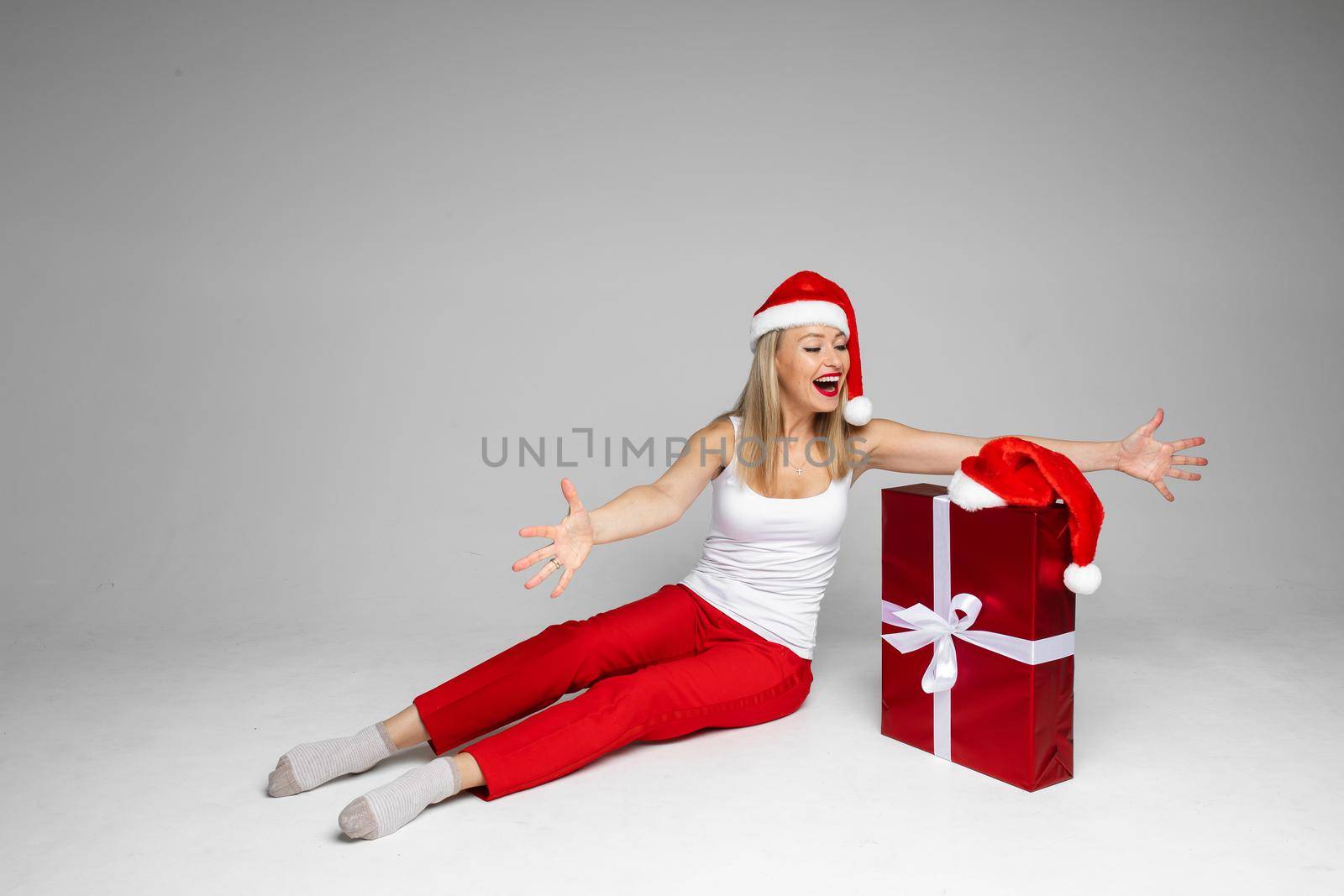 cheerful caucasian woman with red and white hat is very glad to see her gift