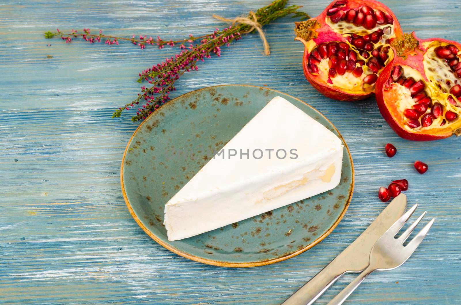 Piece of brie light cheese on blue wooden background. Studio Photo