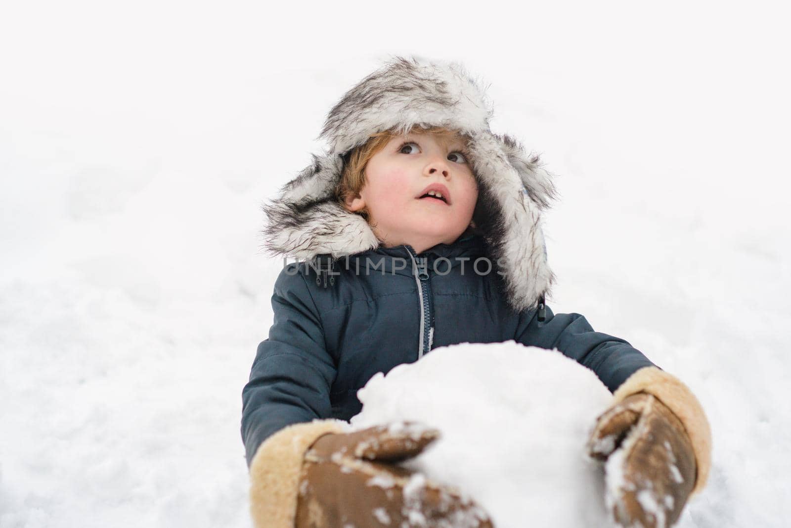 Funny boy posing on winter weather. Child playing with Snow ball