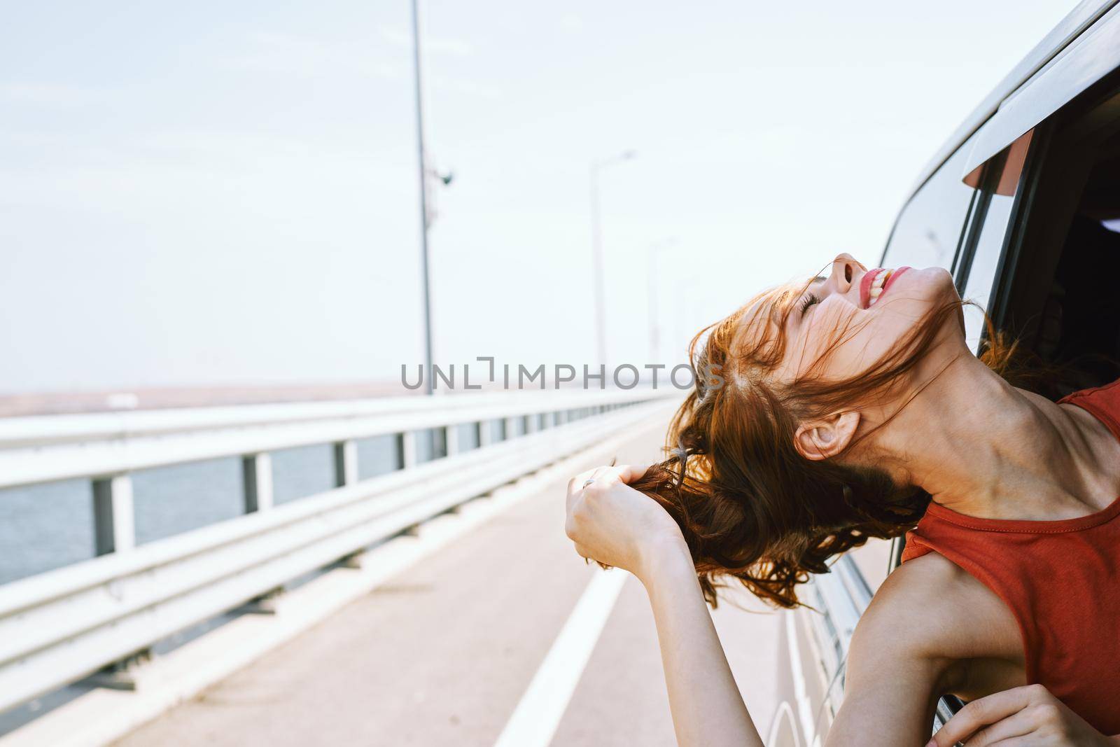 cheerful woman peeking out of the car window trip road travel. High quality photo