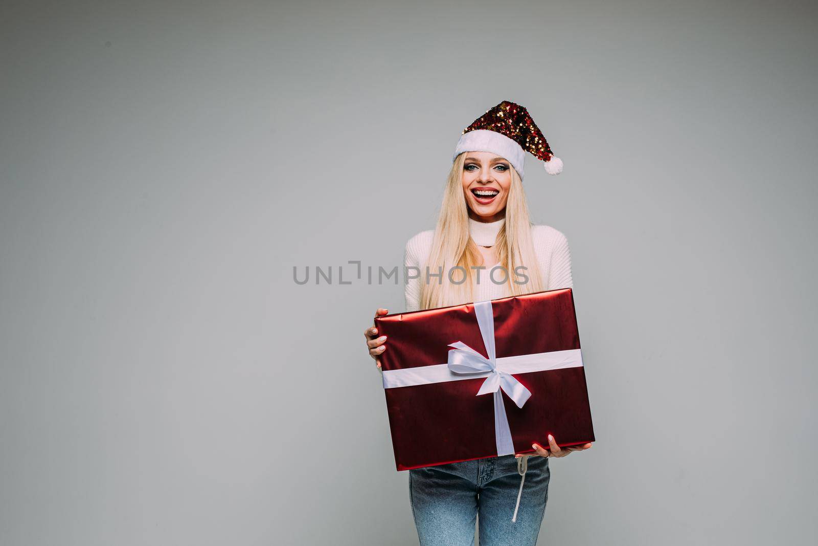 Smiling pretty lady holding red present box with gift ribbon bow by StudioLucky