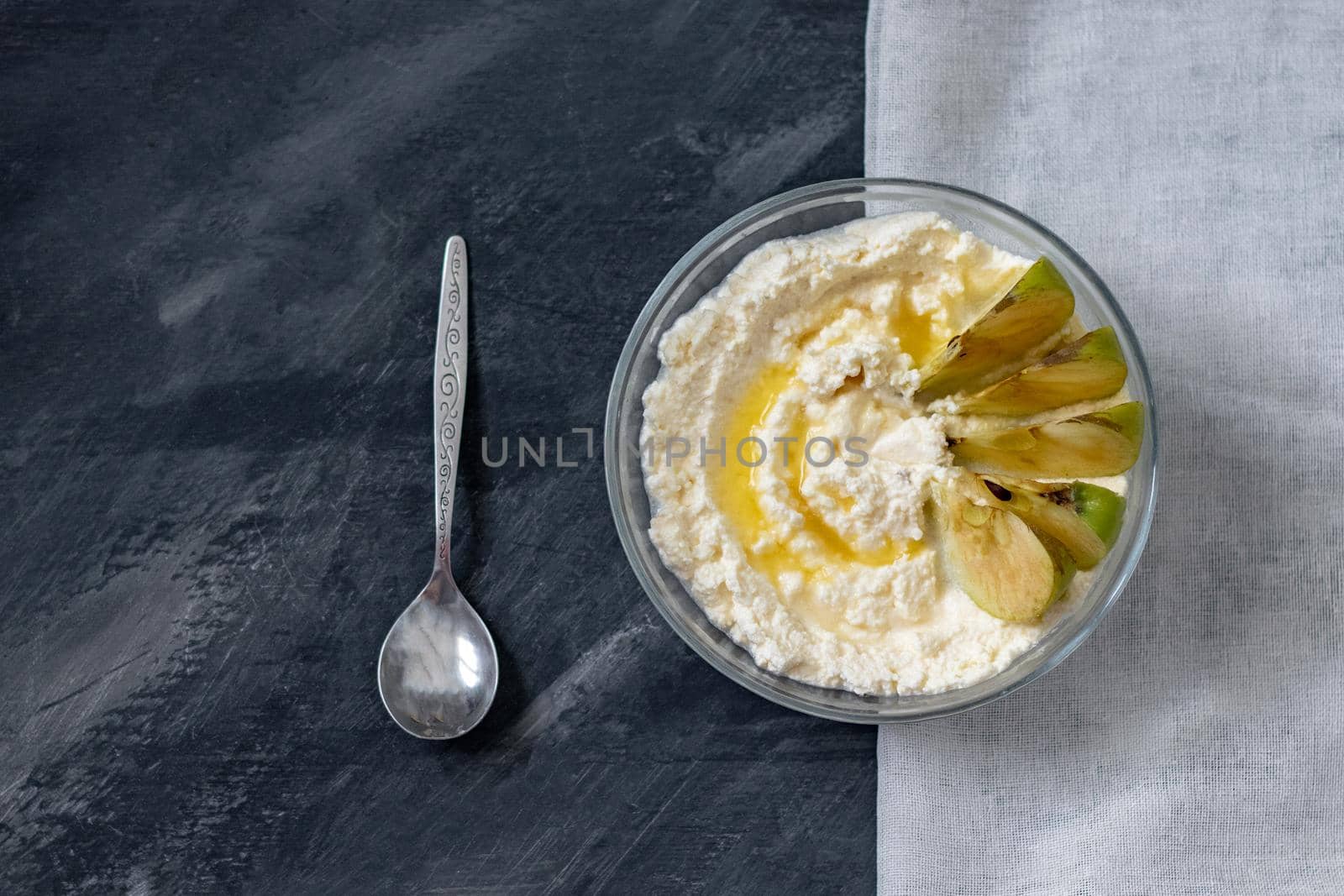 cottage cheese poured with yellow syrup with fresh apples, dark background, top view