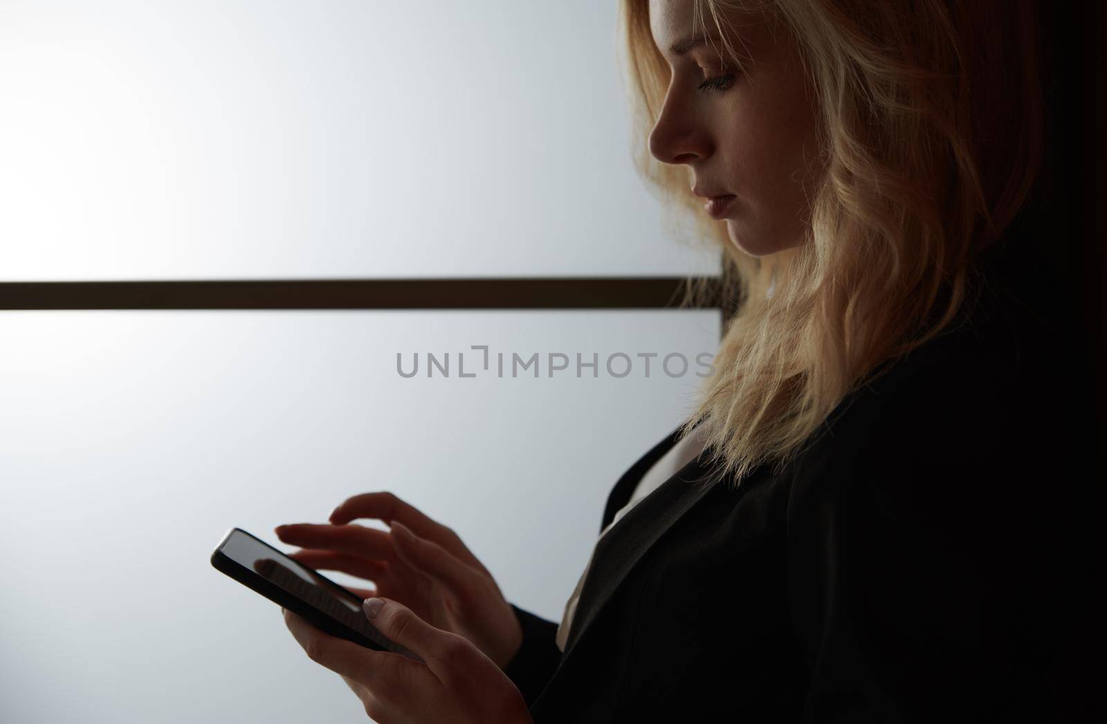 Young adult woman using smartphone at the office by Novic