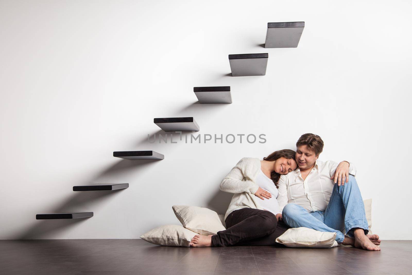 Couple at home sitting on stairs. Pregnant woman