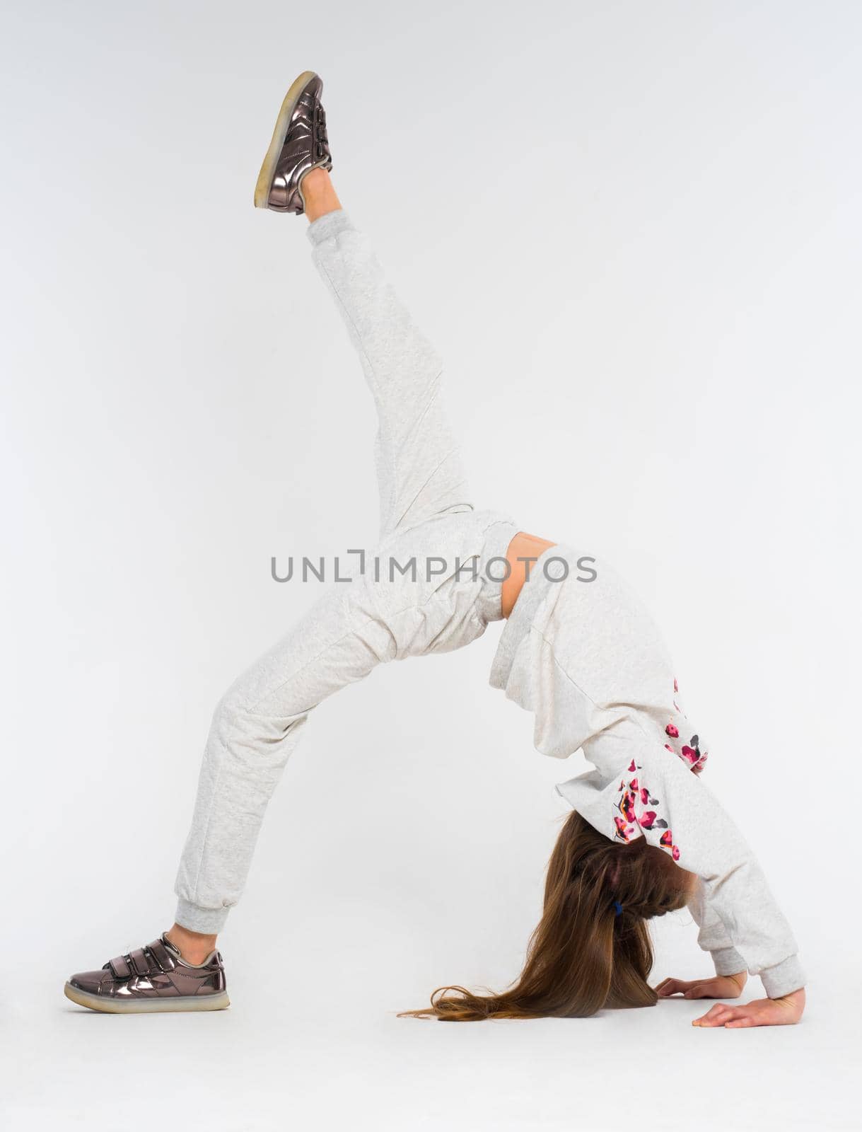 Young girl doing bridge position on the one leg support, one leg extended upwards