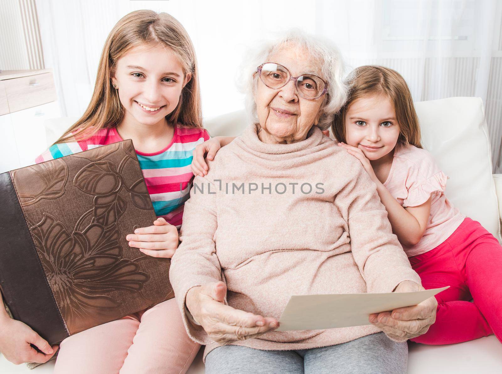 Smiling grandmother with granddaughters looking old photos together