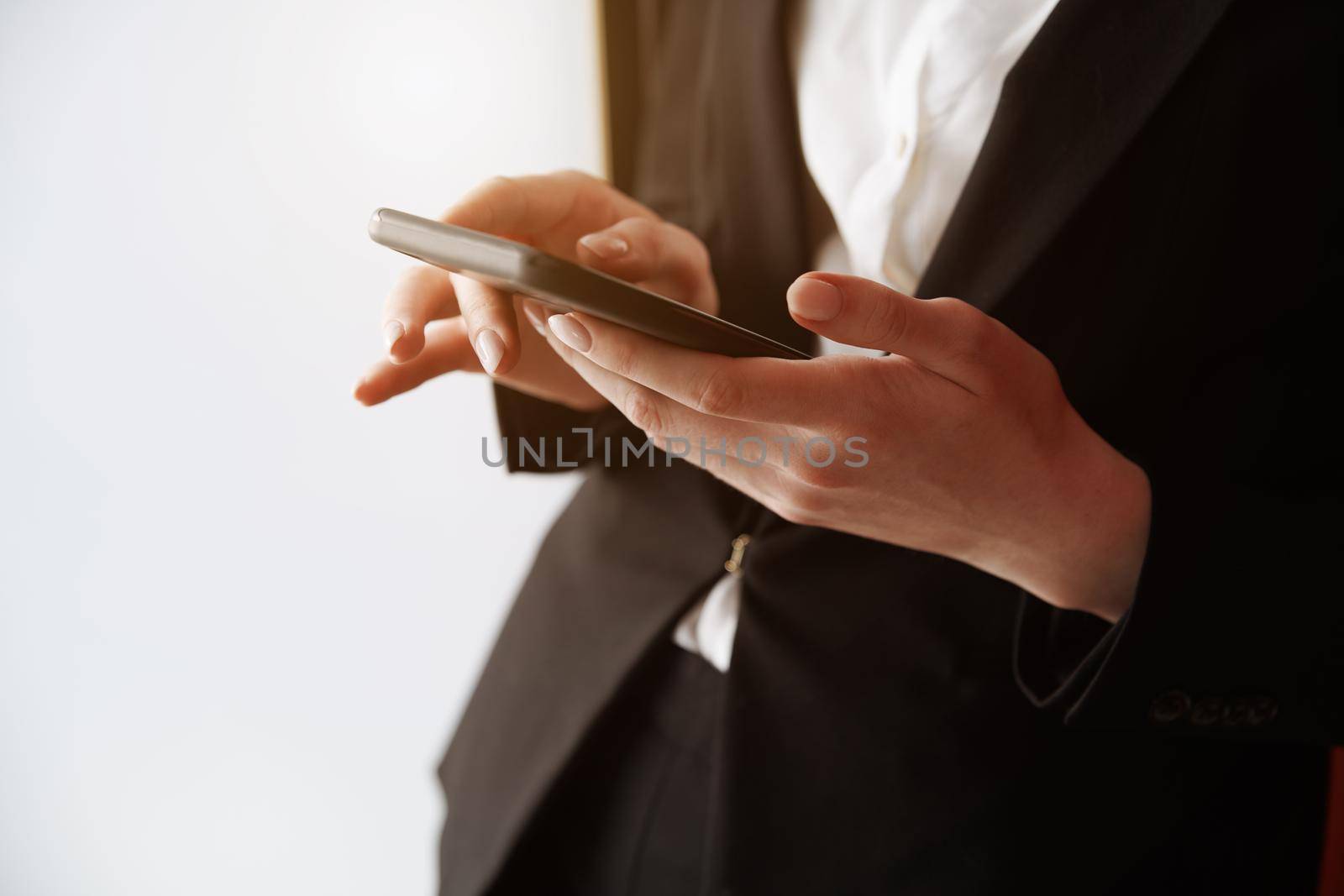 Young adult woman using smartphone next to the white wall