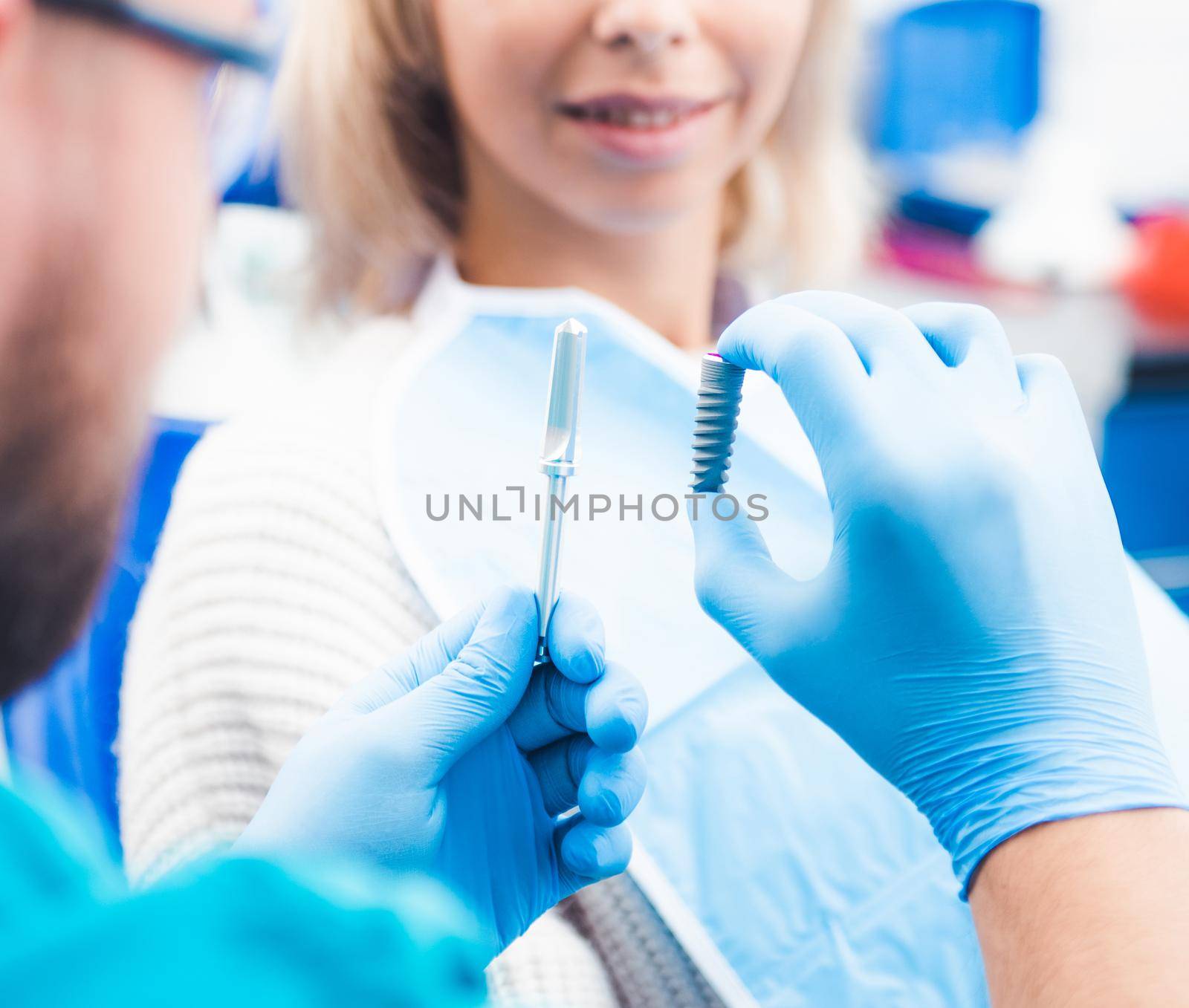 Dentist holding gray implant model with equipment