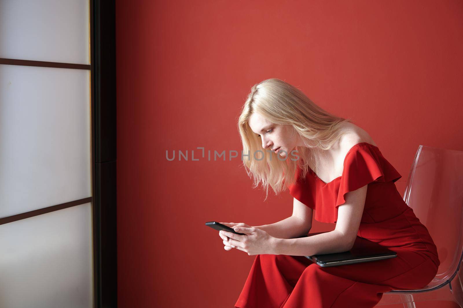 Young adult woman using smartphone and holding laptop