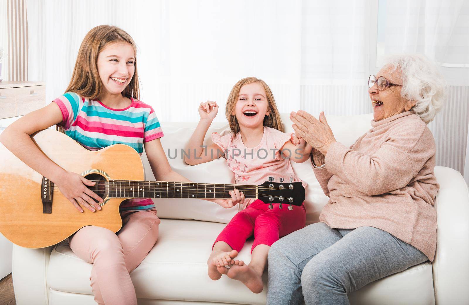 Joyful granddaughters with grandmother listening the guitar play
