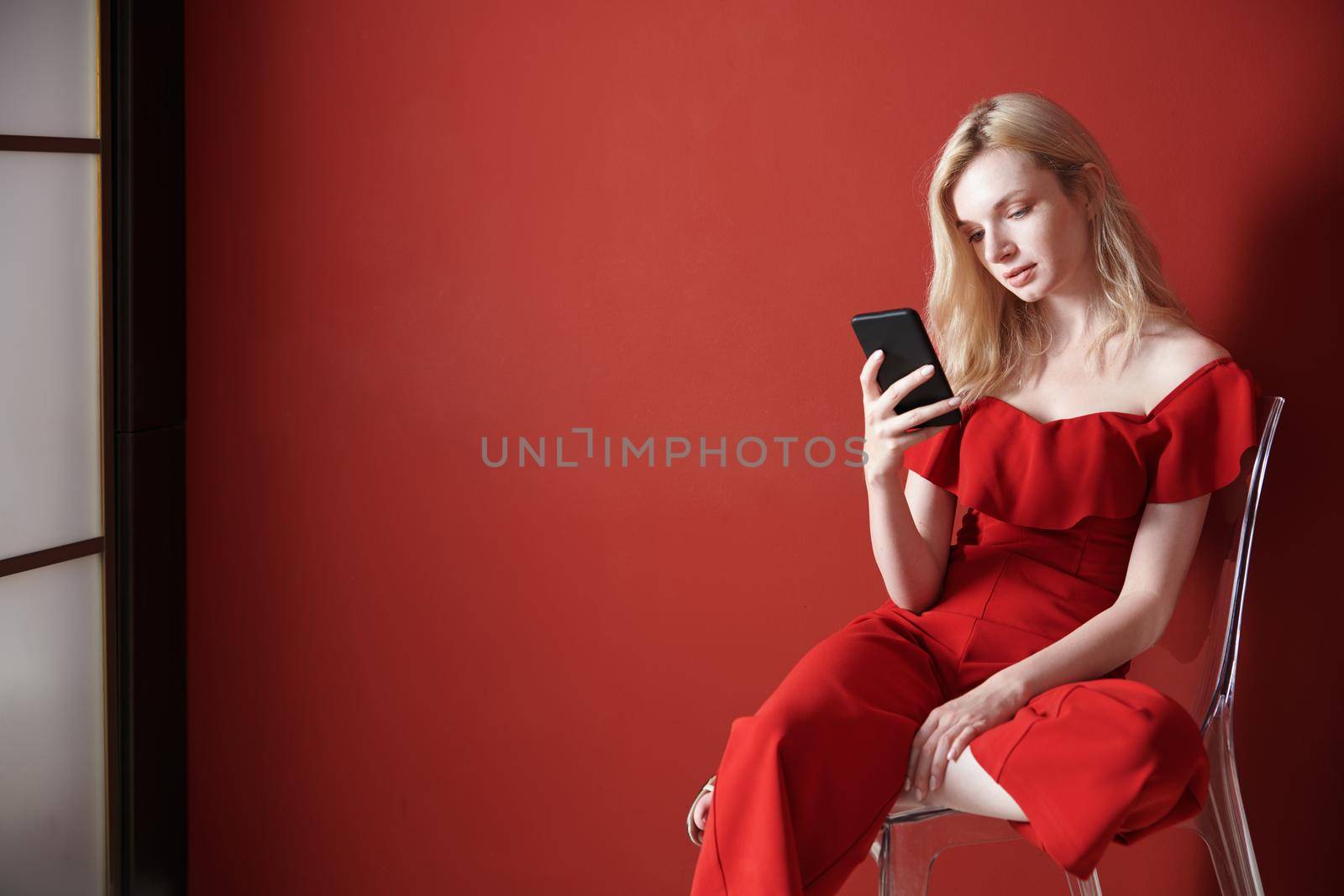 Young adult woman relaxing on a chair and using smartphone 