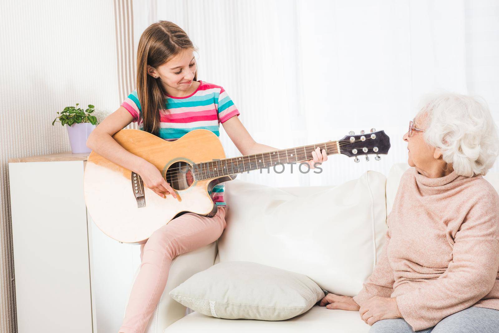 Grandmother listening granddaughter playing guitar