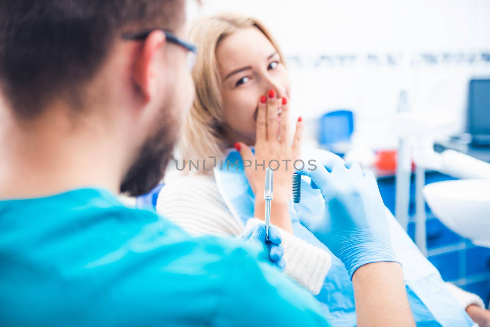 Dentist showing gray implant model to patient