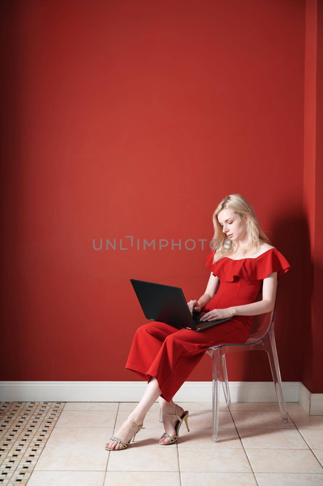 Young adult woman sitting on a chair and working on laptop