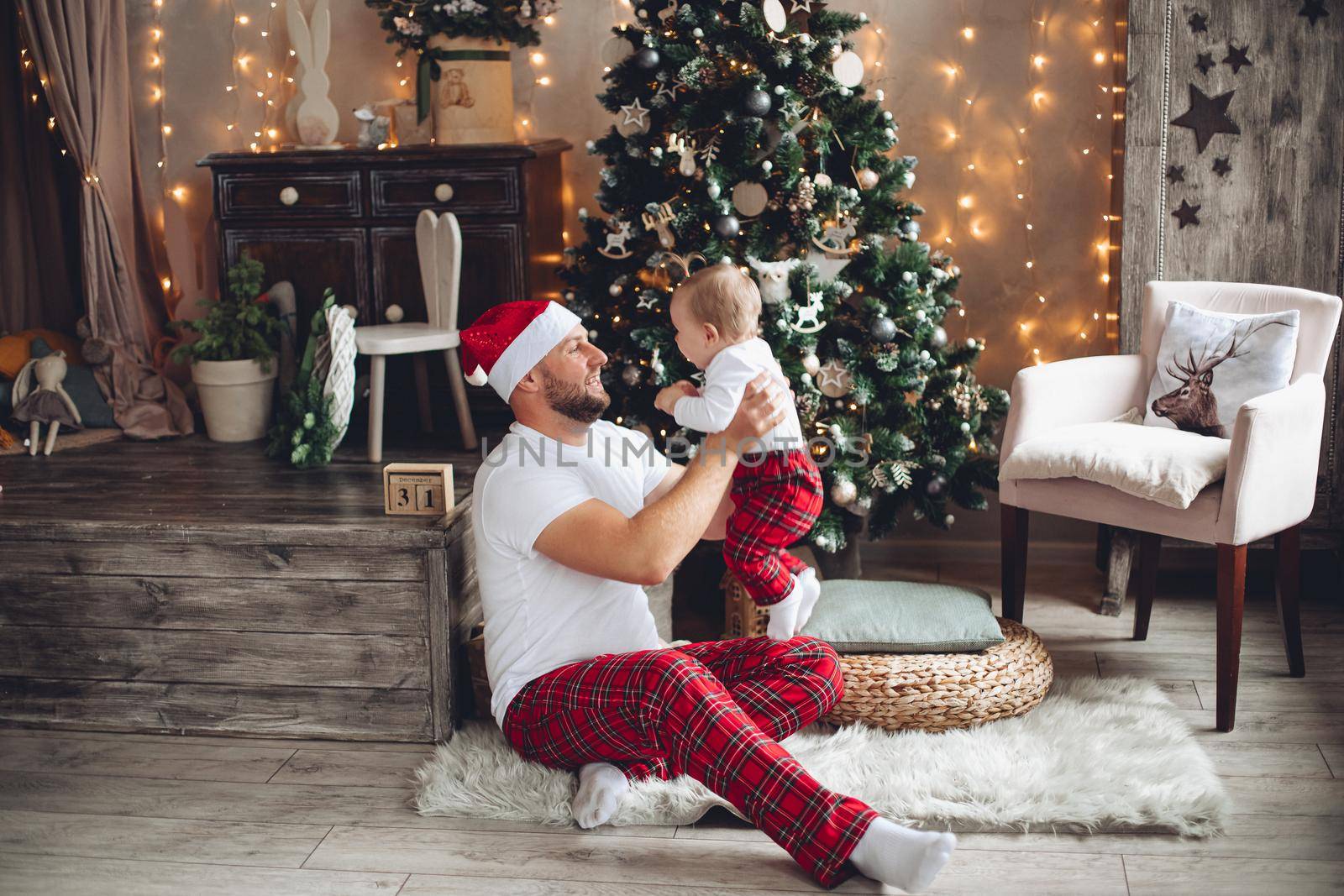 Cheerful caucasian father and his little baby in the same sleepwears celebrate new year